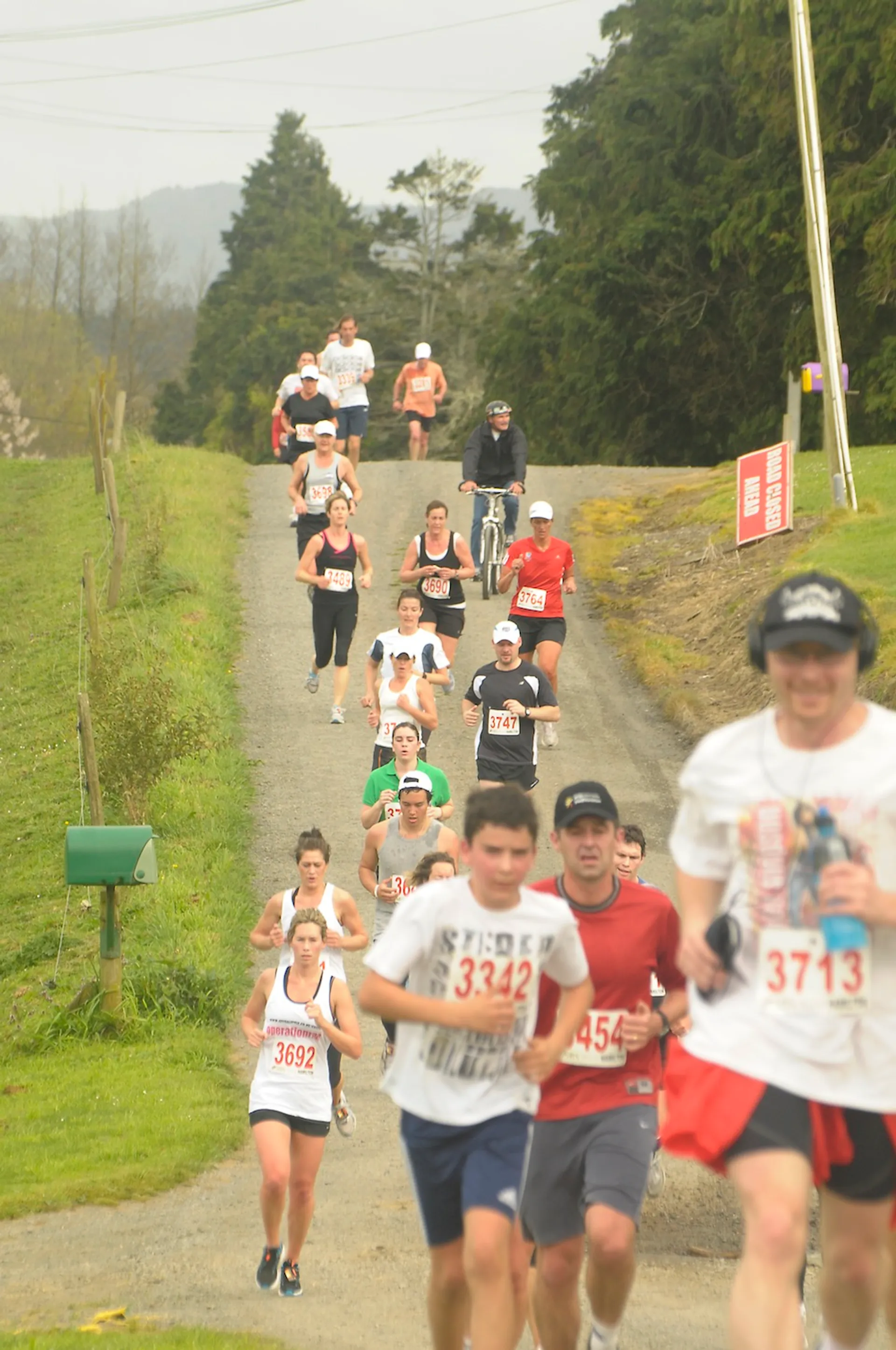 The image depicts a group of people participating in a road race or running event.