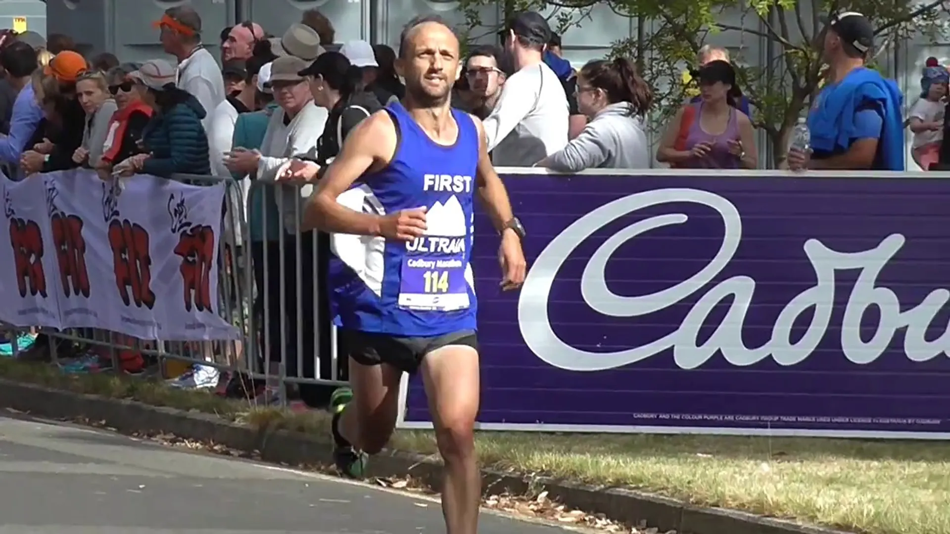 The image depicts a male runner in a blue tank top, labeled with the number