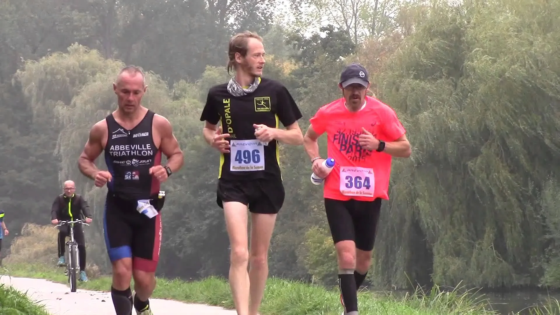 The image shows three individuals participating in a running event. They appear to be mid