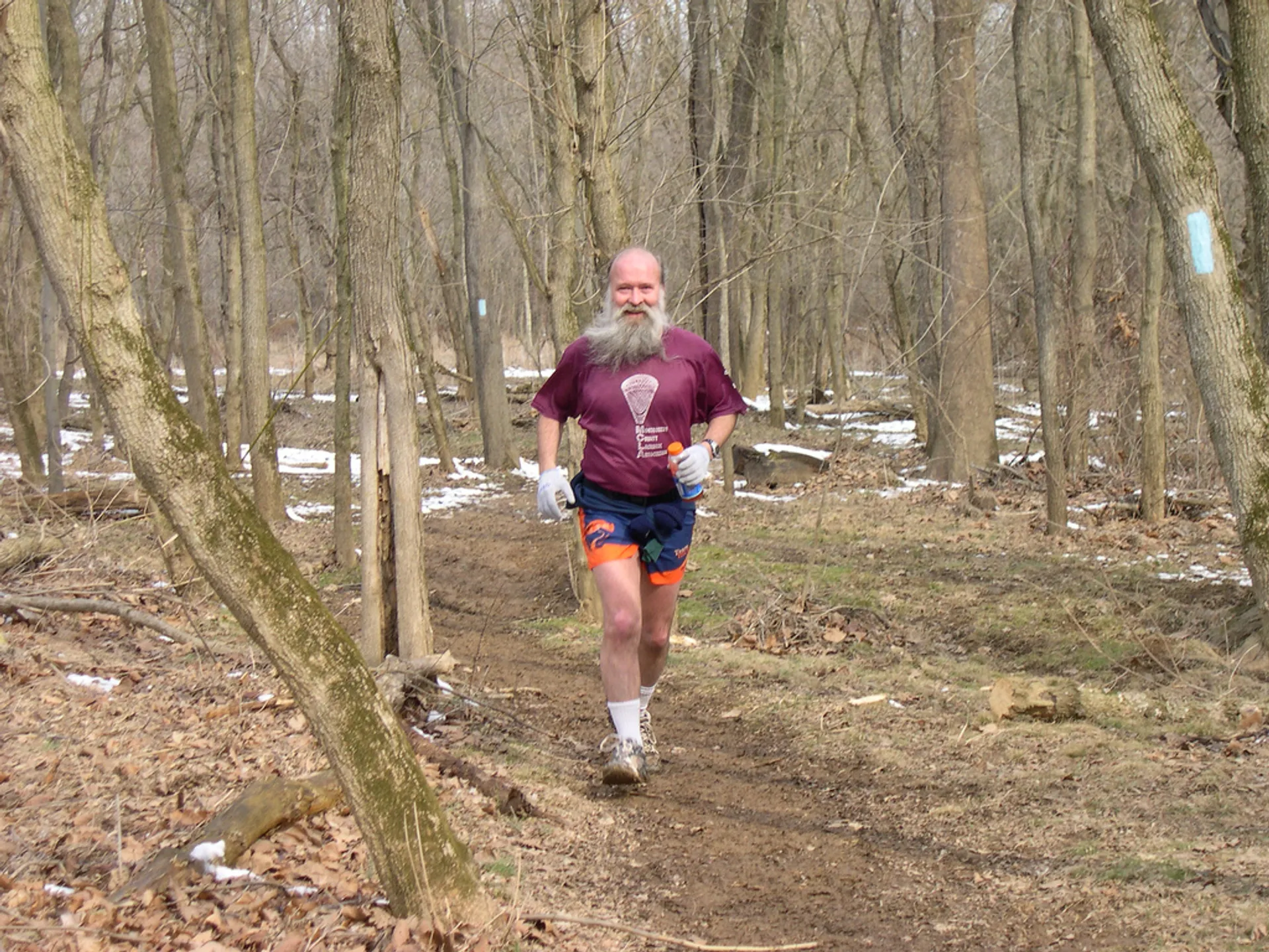 The image depicts a person jogging on a trail through a wooded area. The person
