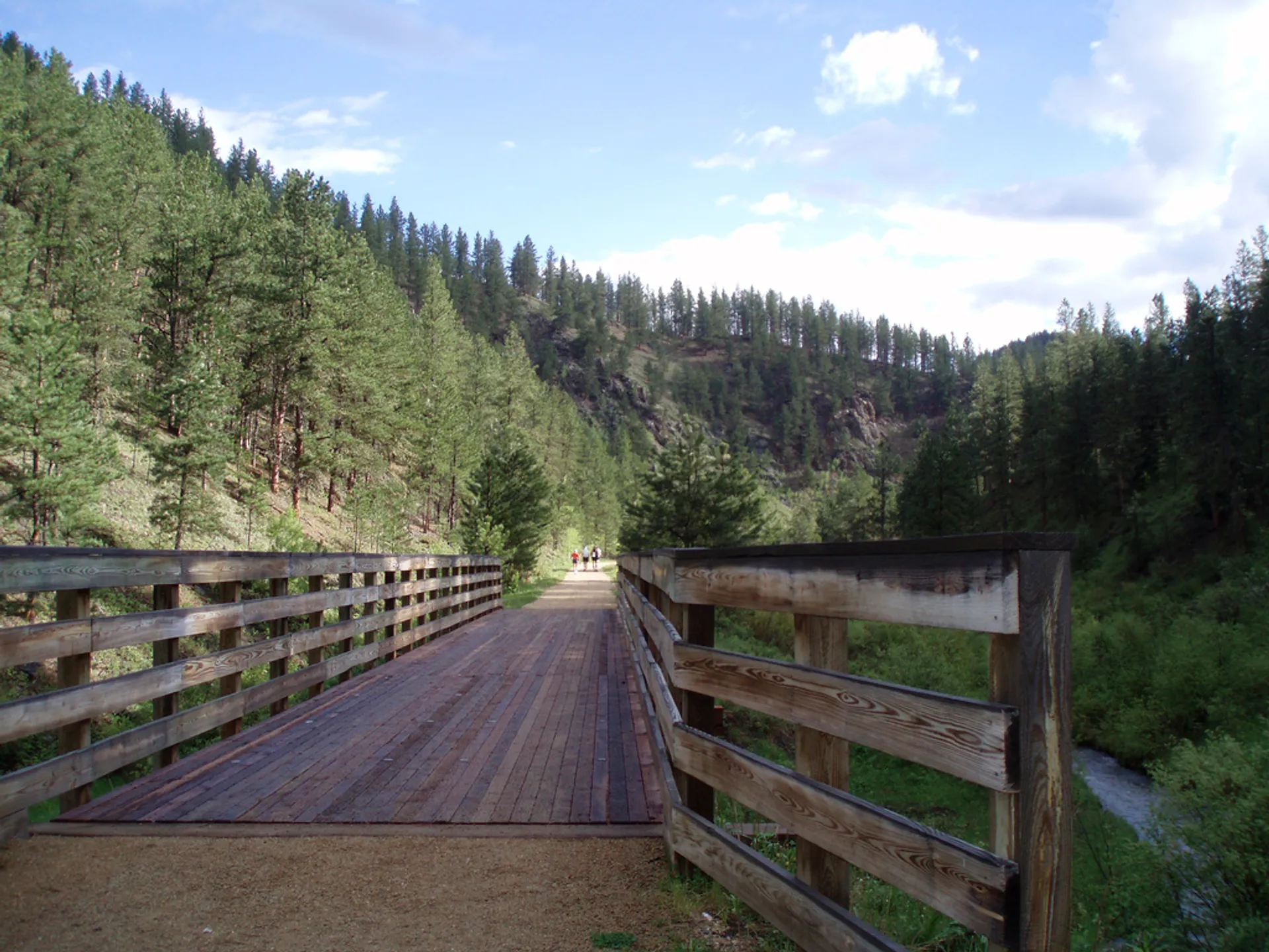 The image shows a wooden bridge with a railing on both sides. The bridge spans