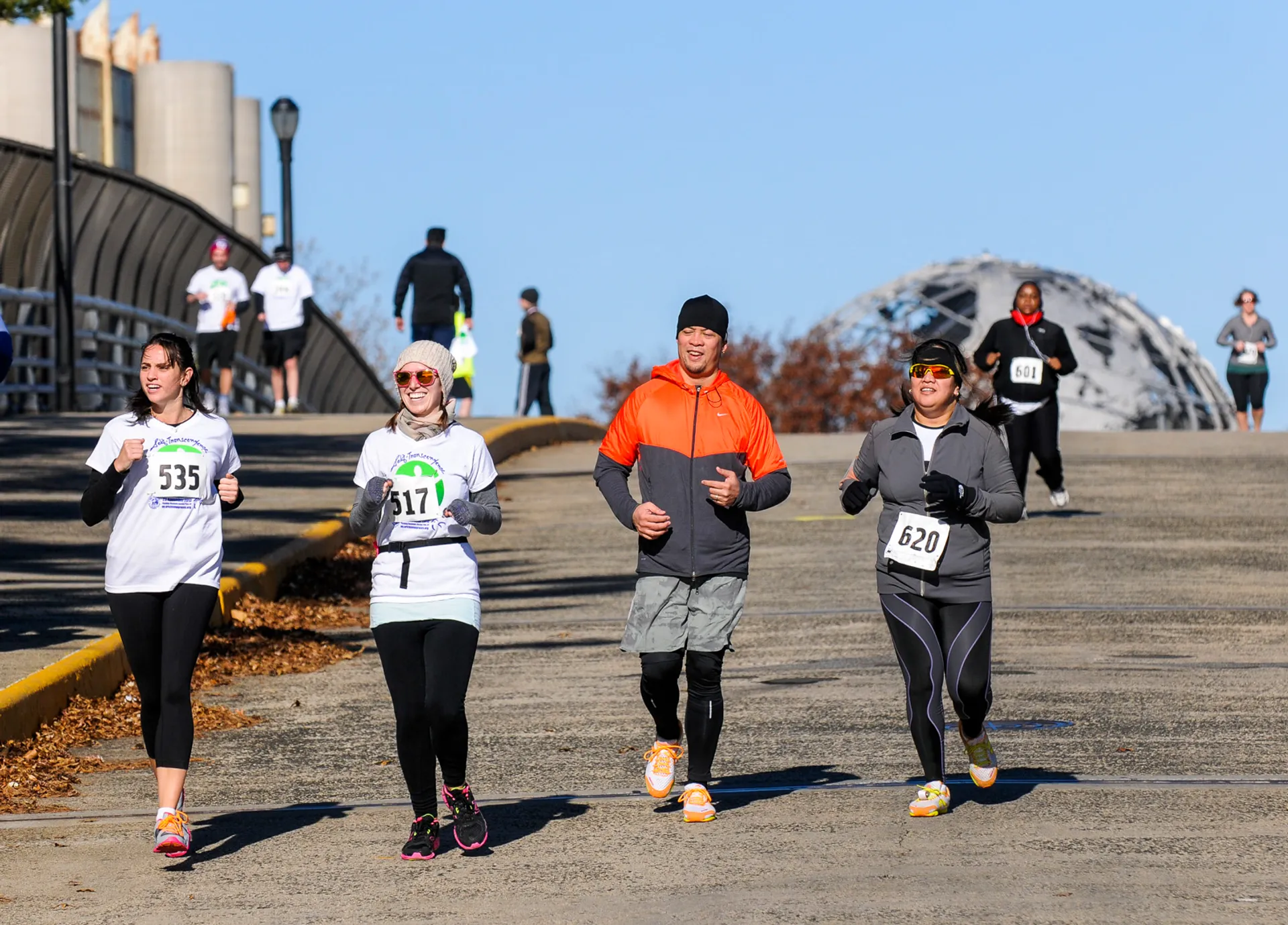 The image shows a group of people participating in a running event or race. They