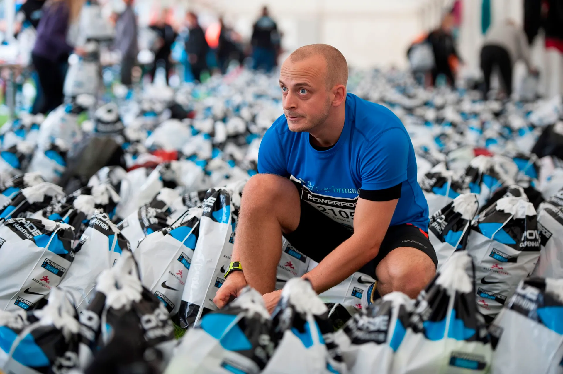 The image shows a person amidst a large number of bags laid out on the ground