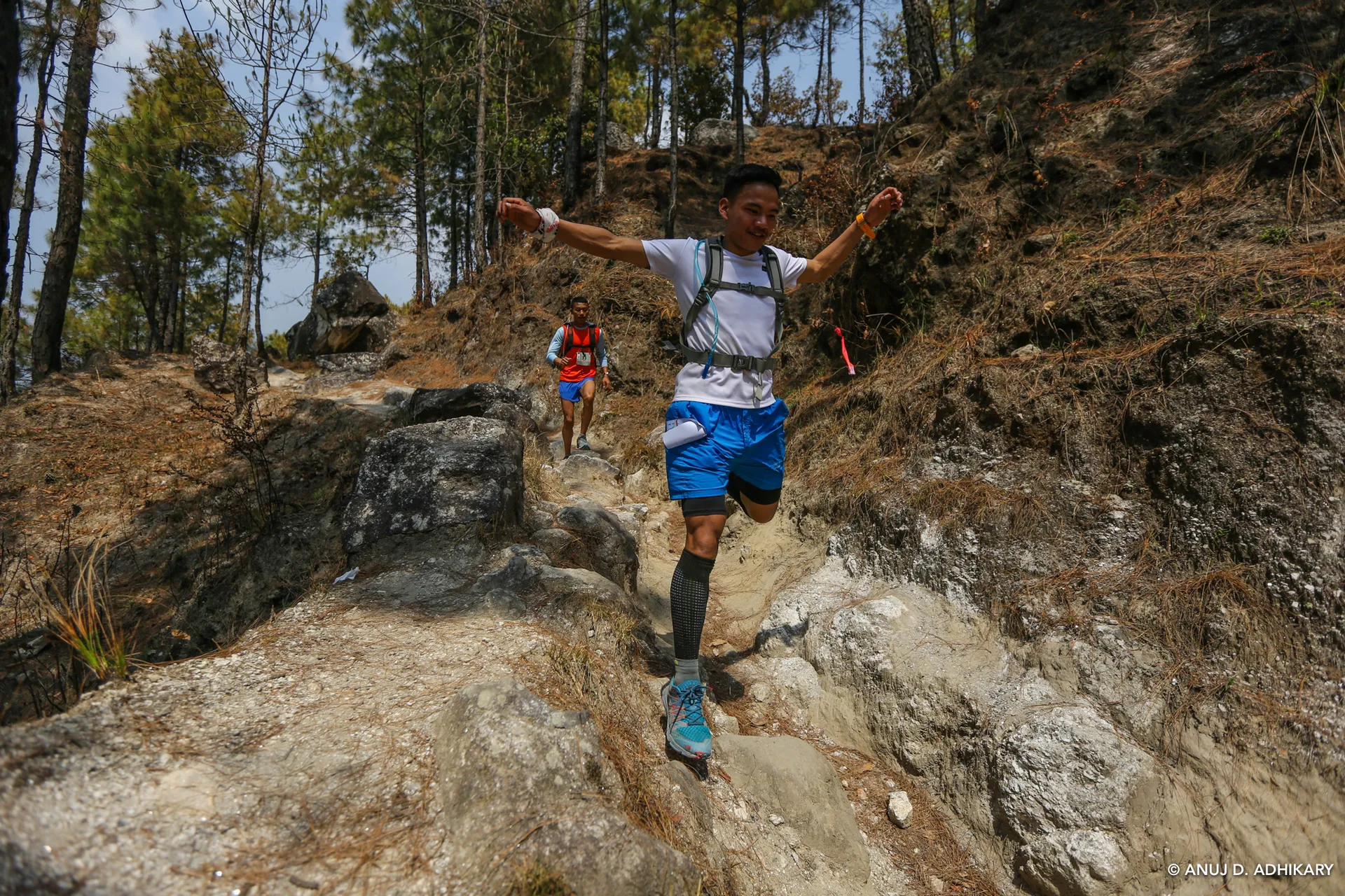 This image captures two individuals engaged in a trail running activity, possibly during a competitive