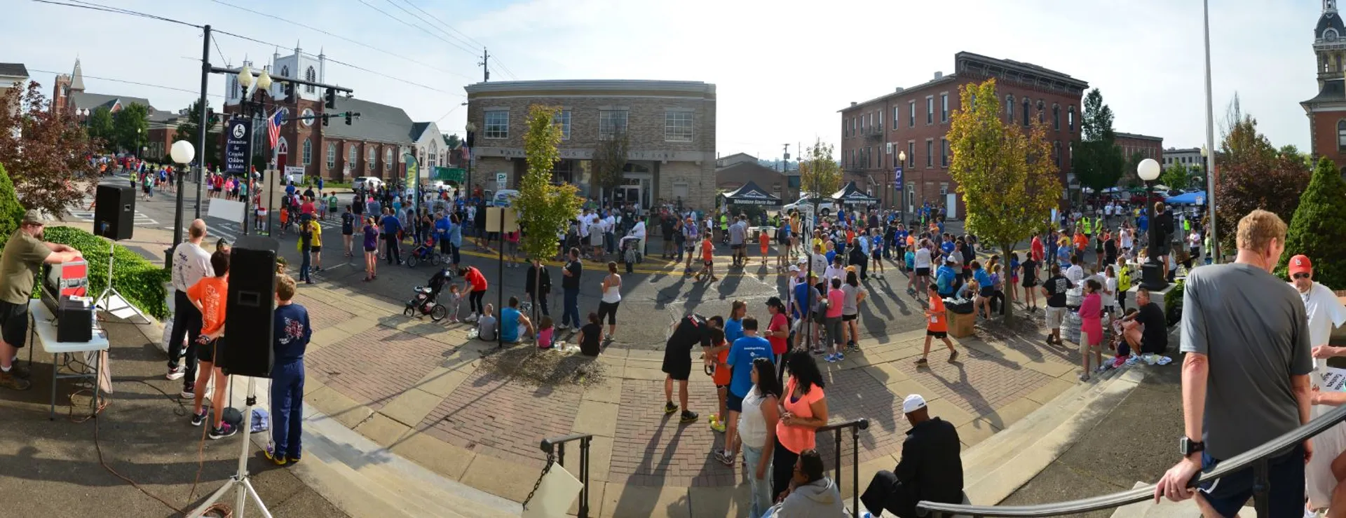 This image displays a panoramic view of a bustling street event. It appears to be