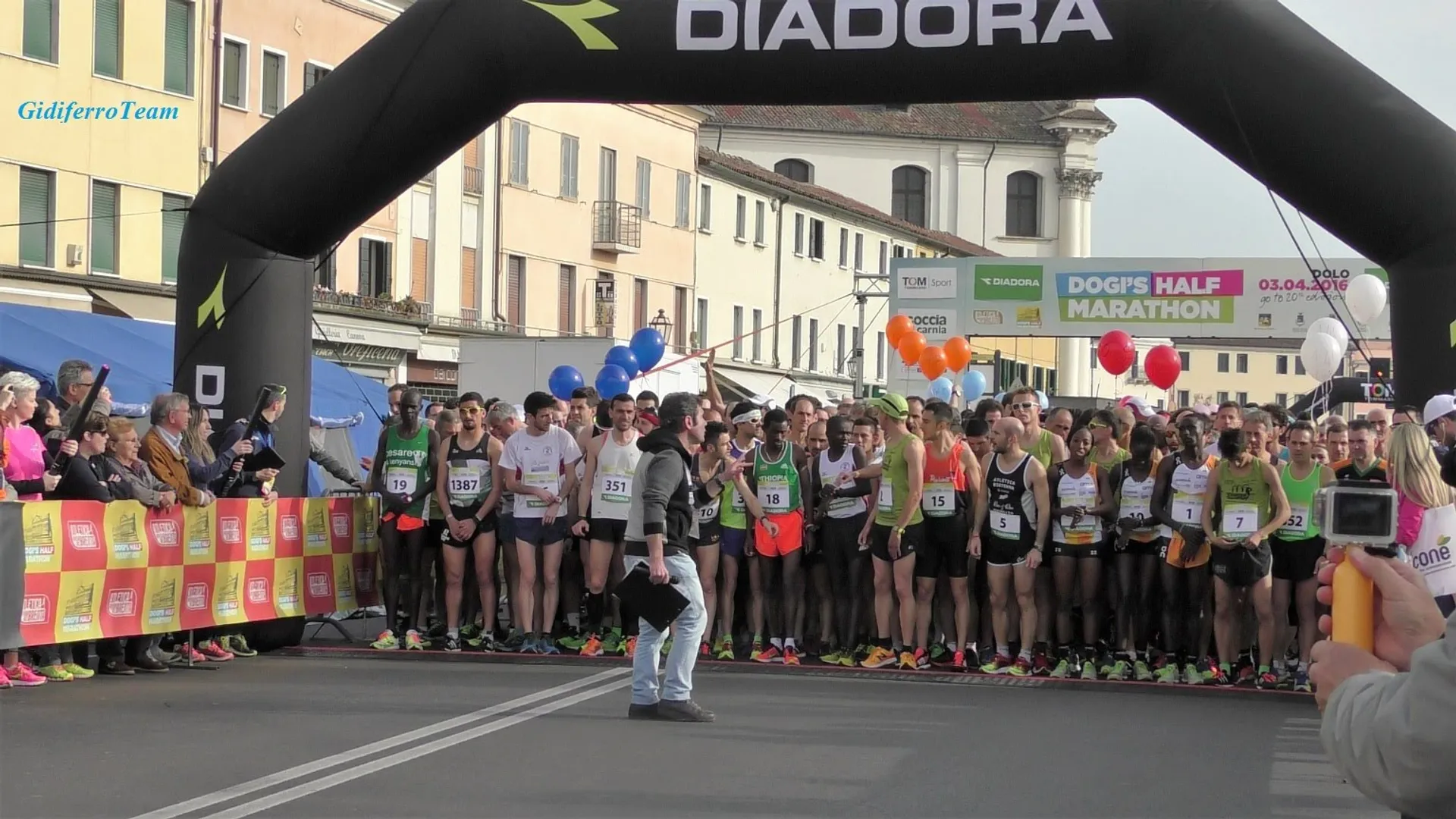 The image shows a group of runners lined up at the starting line of a half