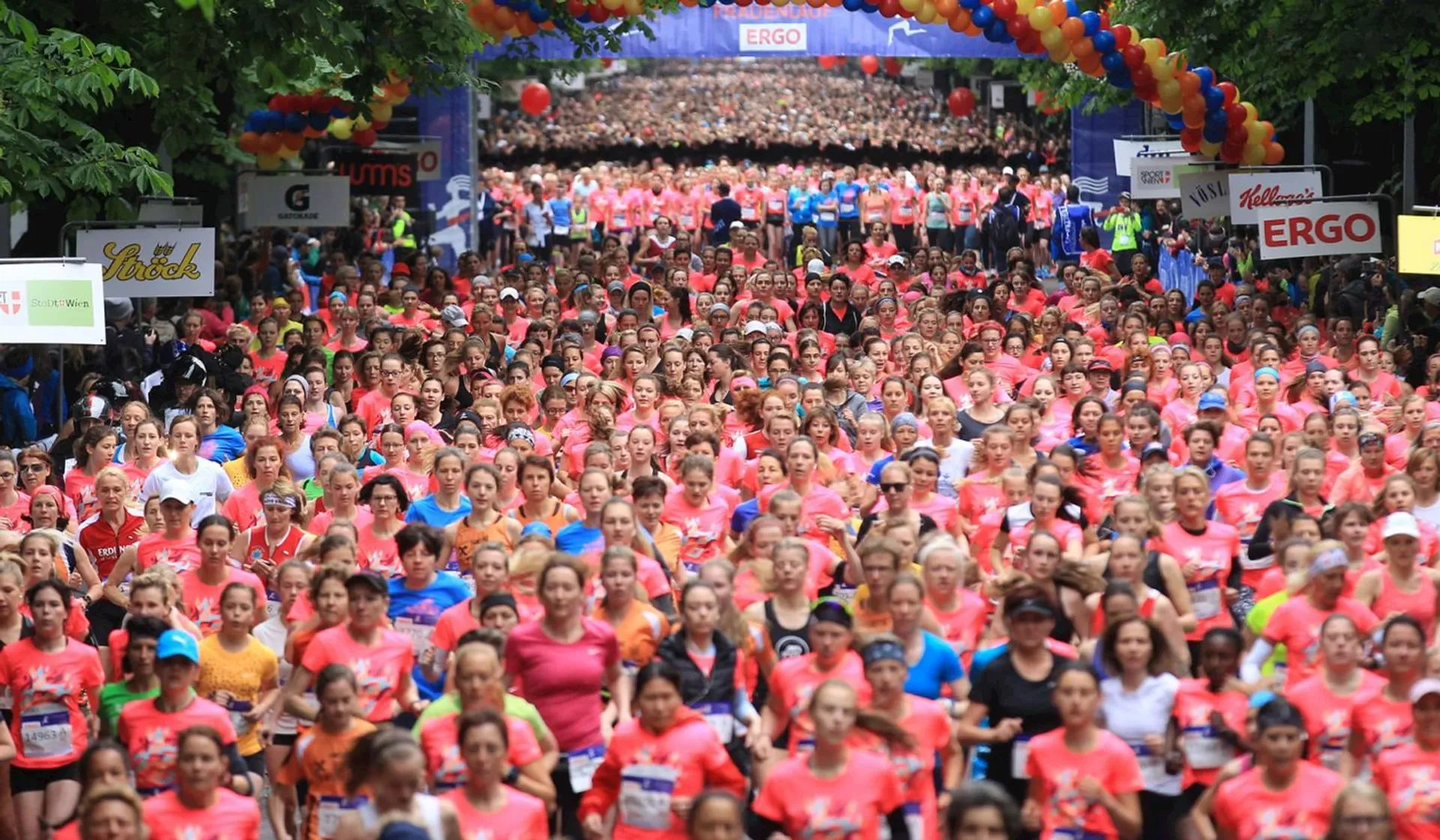 The image shows a large group of participants at the start of a running event.