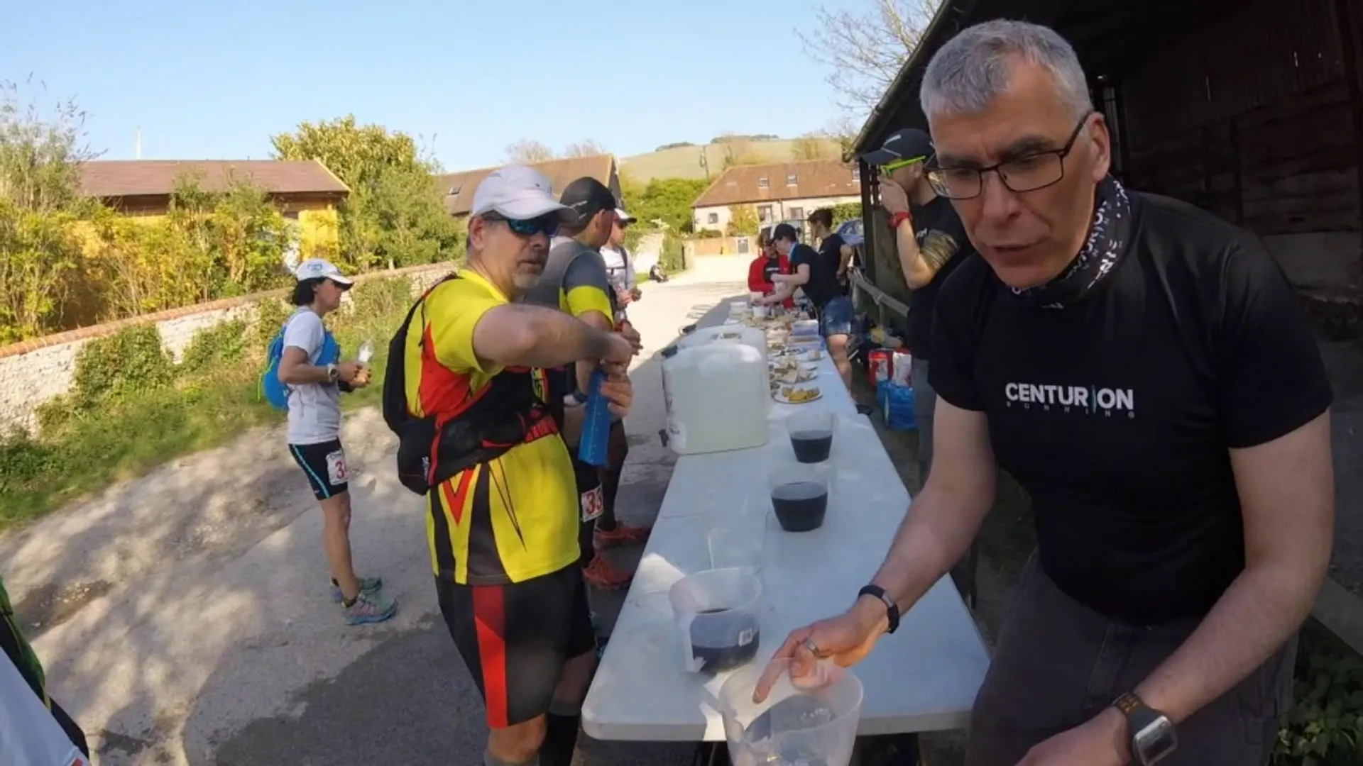 The image shows a group of runners at an aid station during what appears to be