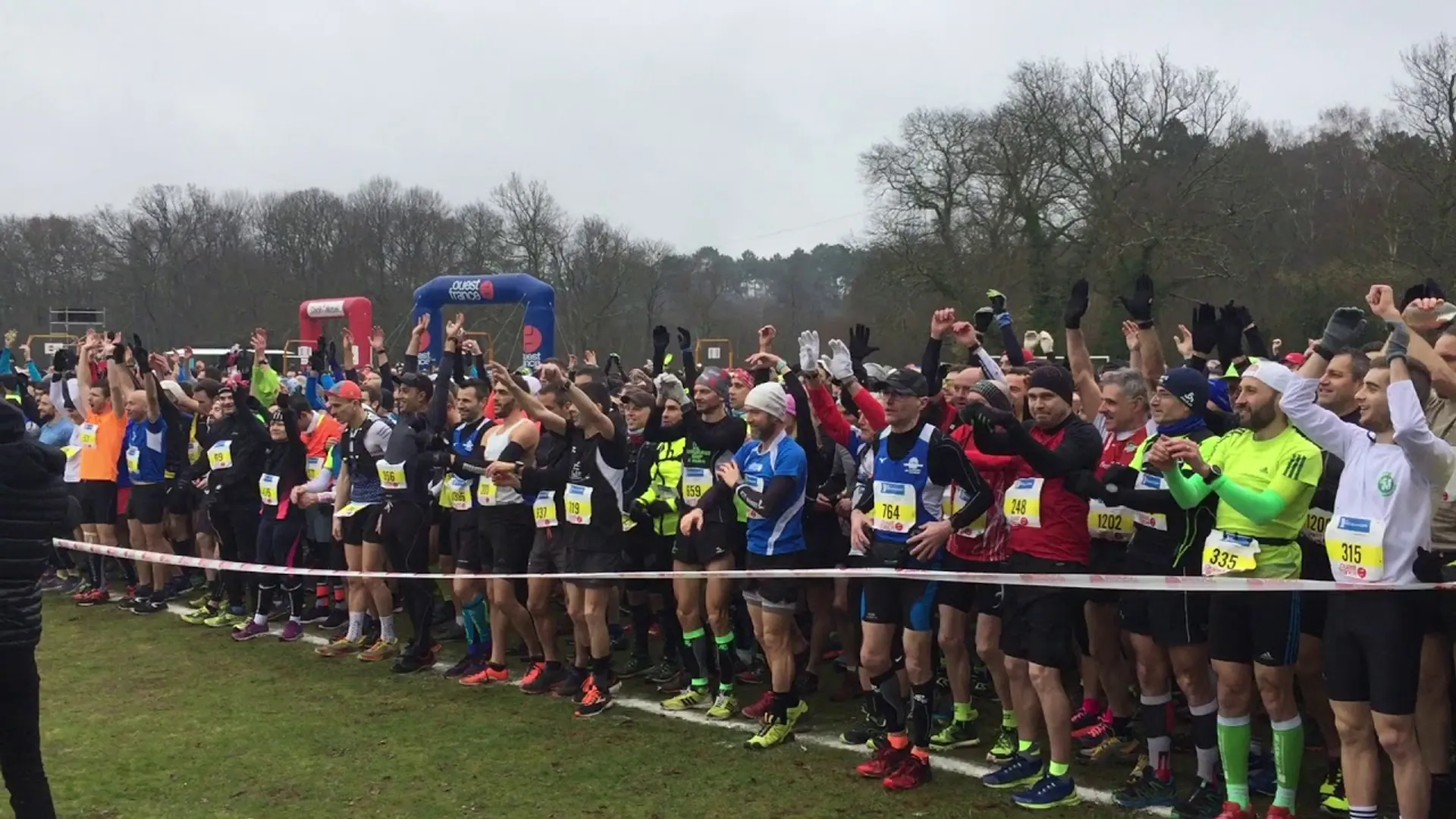 The image shows a group of runners gathered at the starting line of a race.
