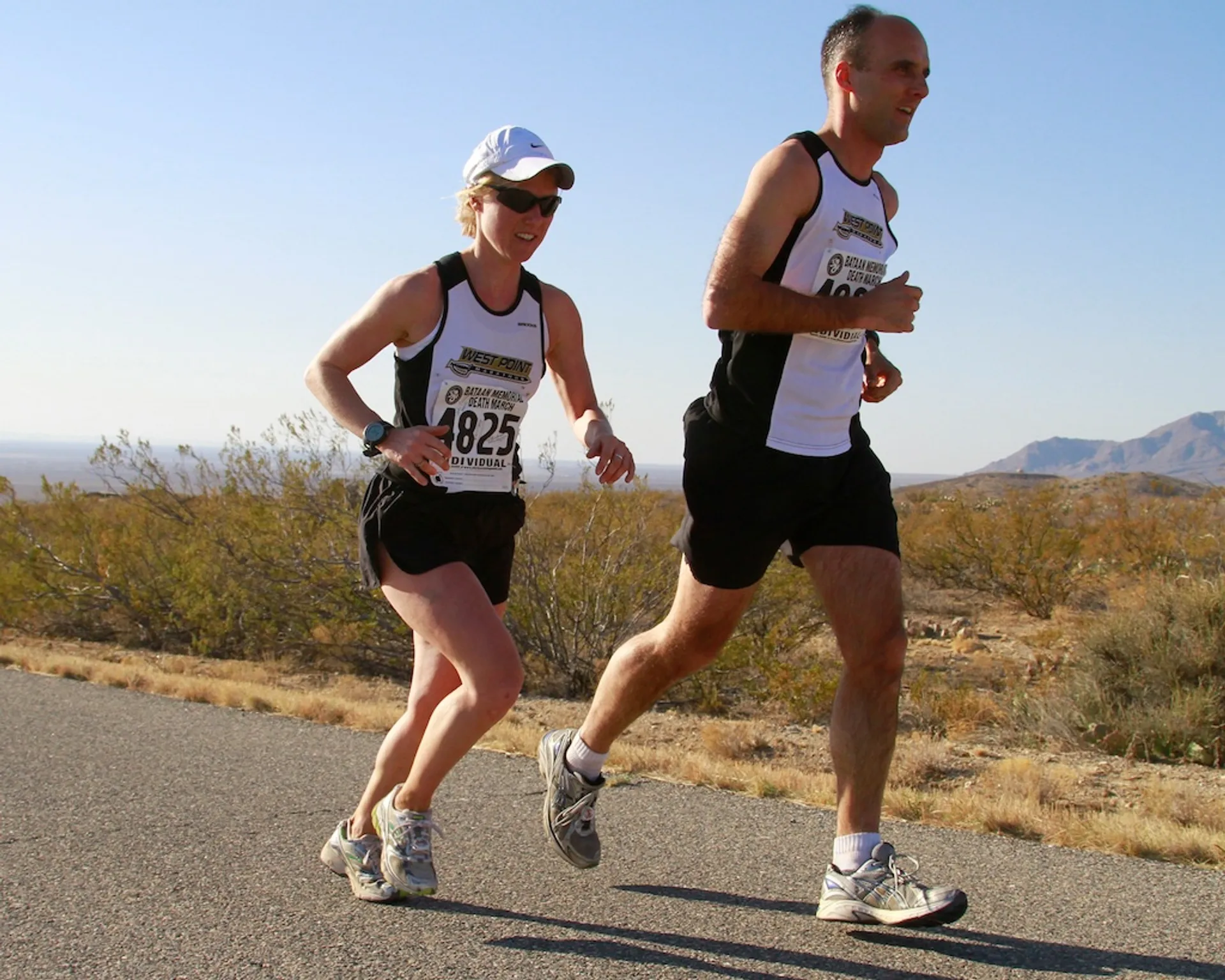 The image depicts two individuals participating in a running event, as indicated by their bib