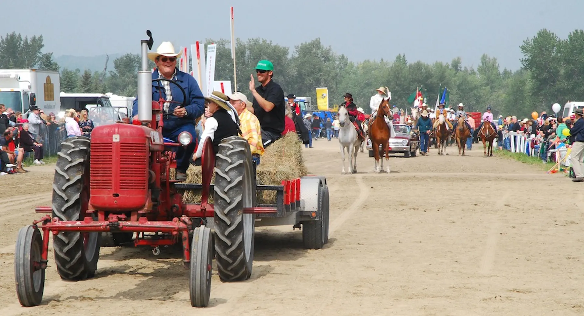 This image depicts a rural event or fair. In the foreground, a vintage red