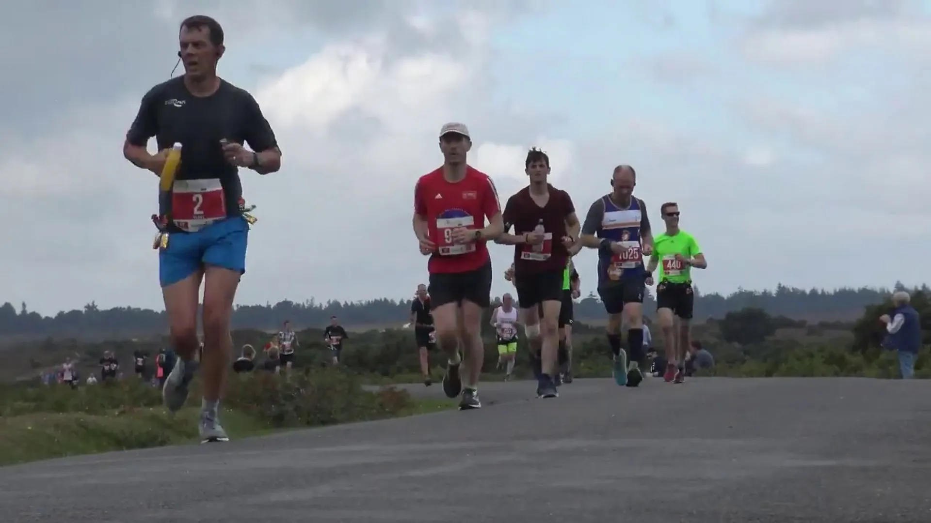 The image shows a group of runners participating in a road race. They appear to