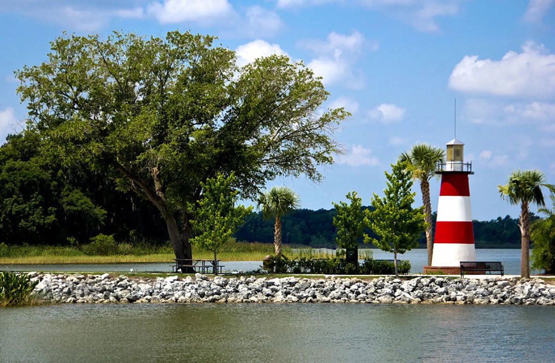 The image shows a scenic landscape featuring a red and white striped lighthouse near a