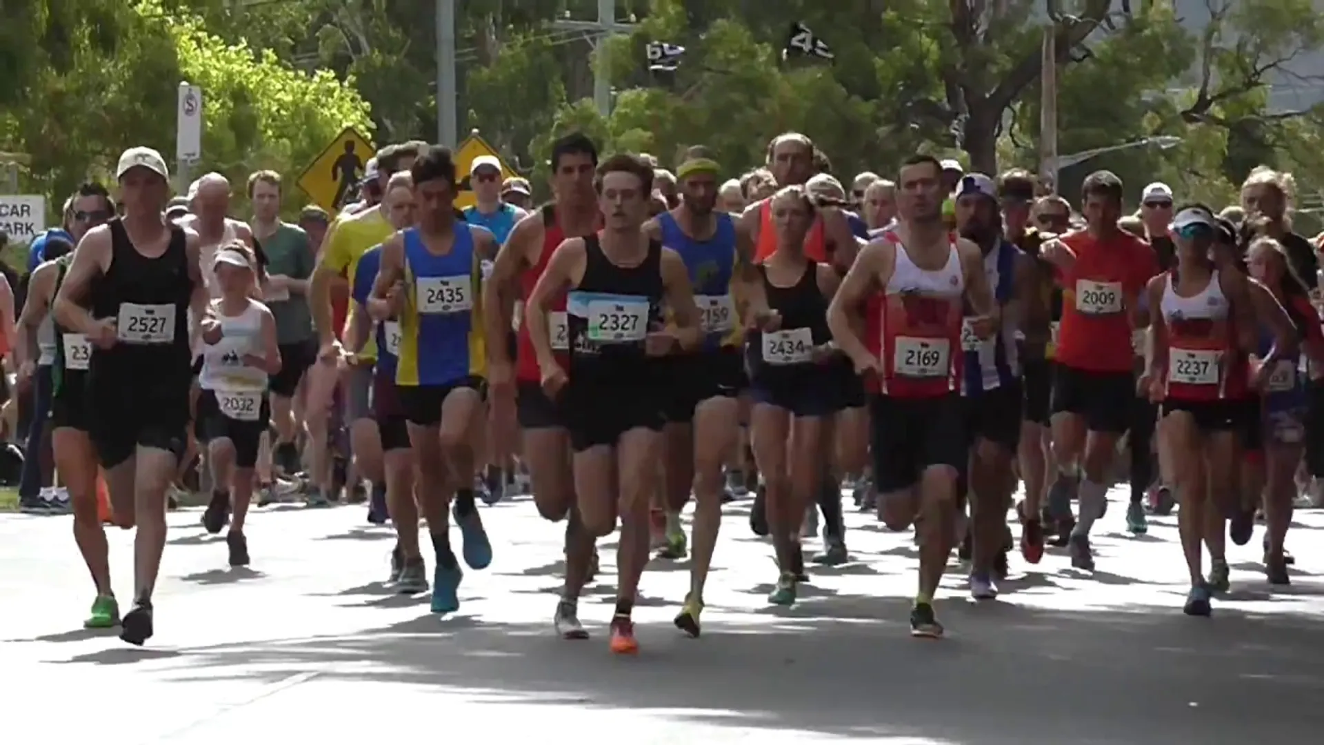 The image shows a group of runners participating in a road race. They are wearing