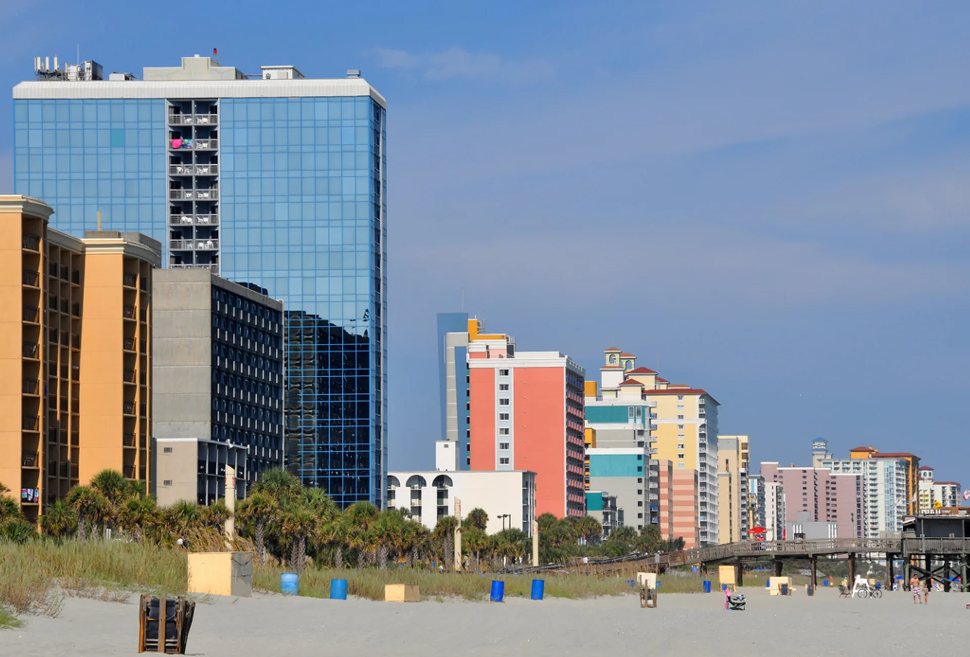 The image features a beach scene with several high-rise hotels and condominium buildings adjacent to