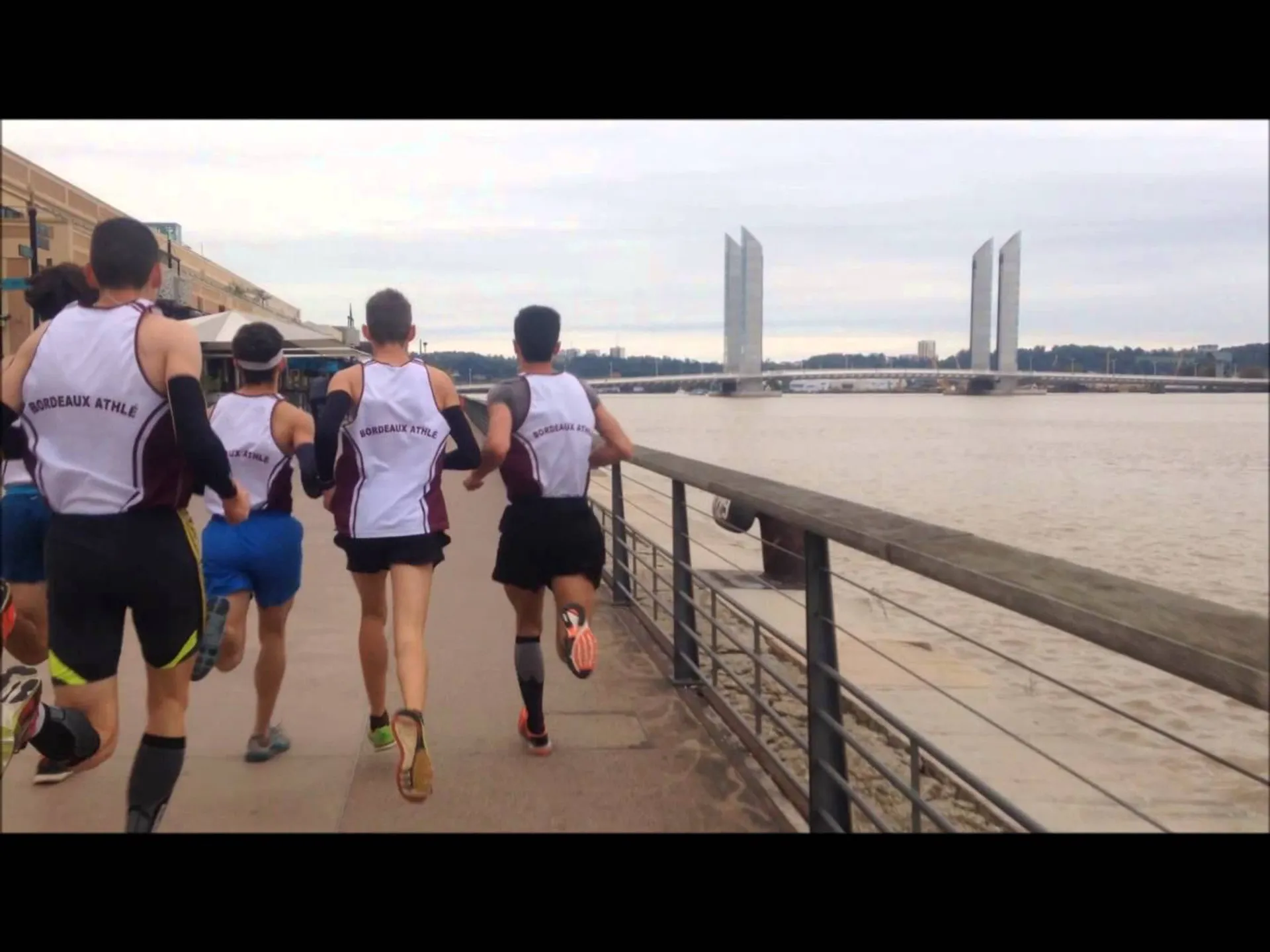 The image shows a group of runners jogging along a riverside path. They appear