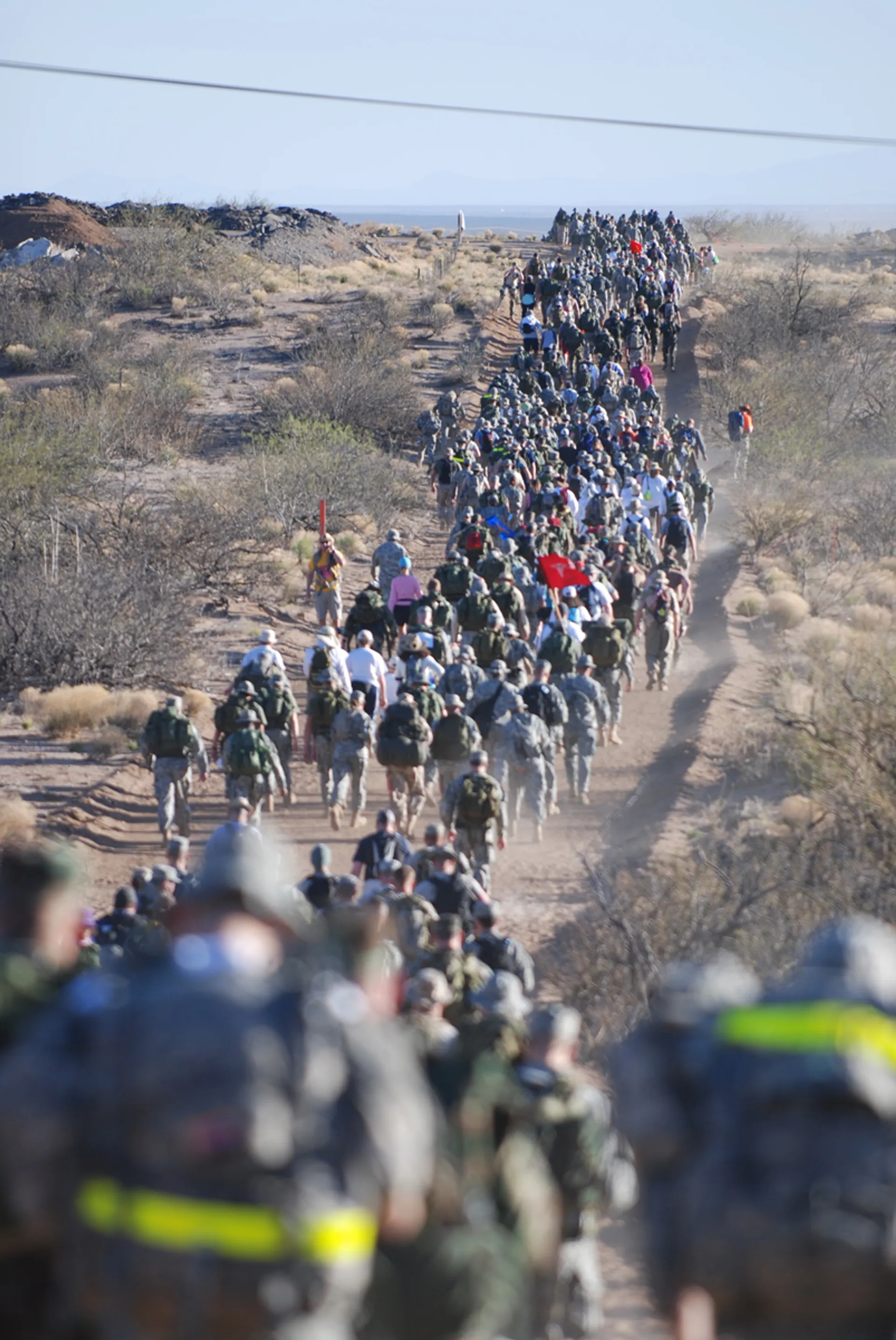 The image displays a long line of individuals marching or walking in what appears to be