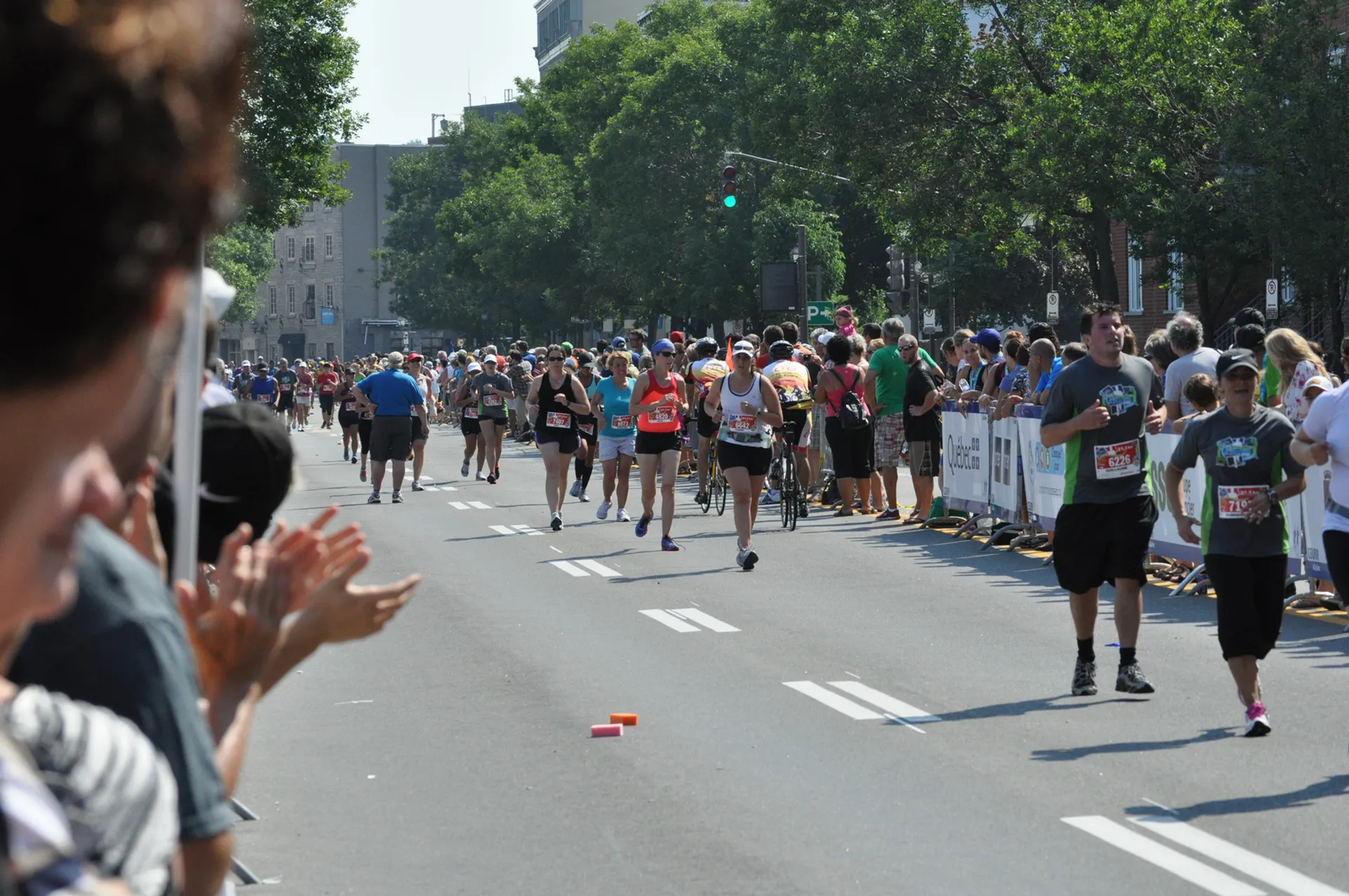 The image shows a group of runners participating in a road race. Spectators can