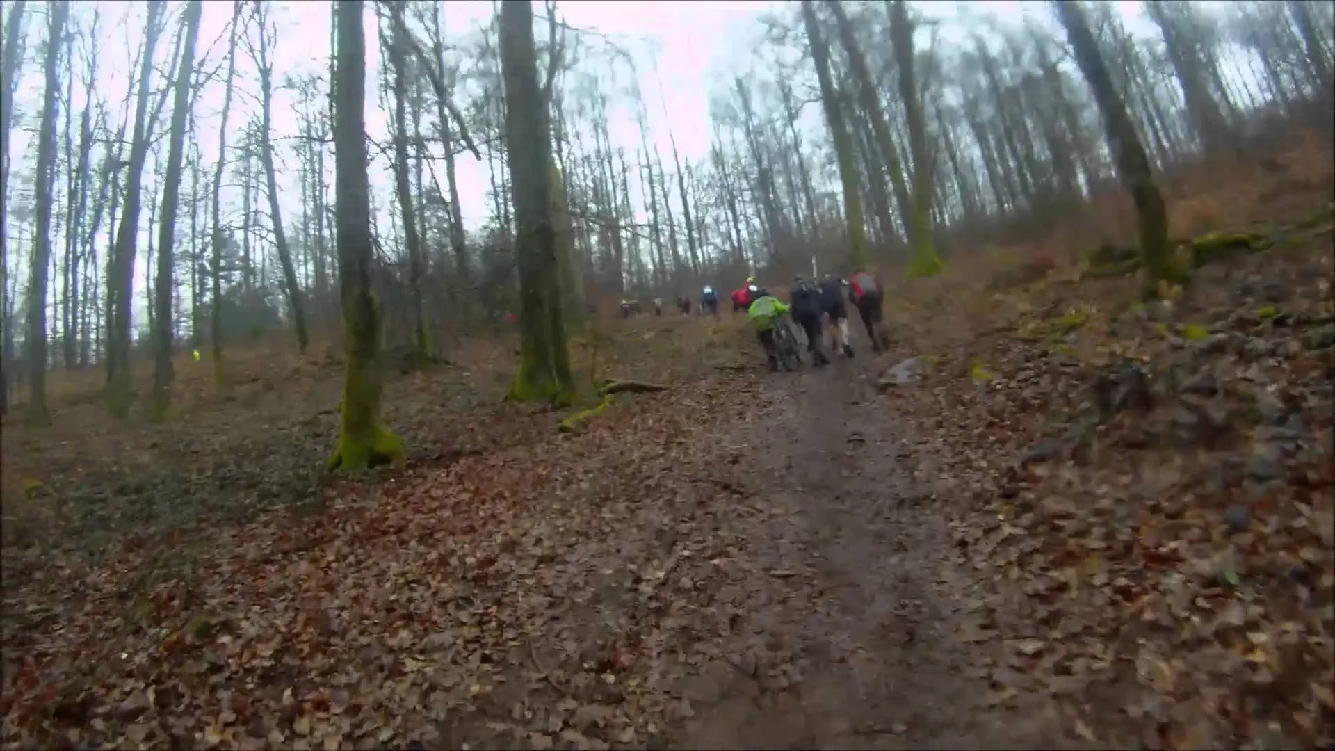 The image shows a group of people hiking or walking along a muddy trail in a