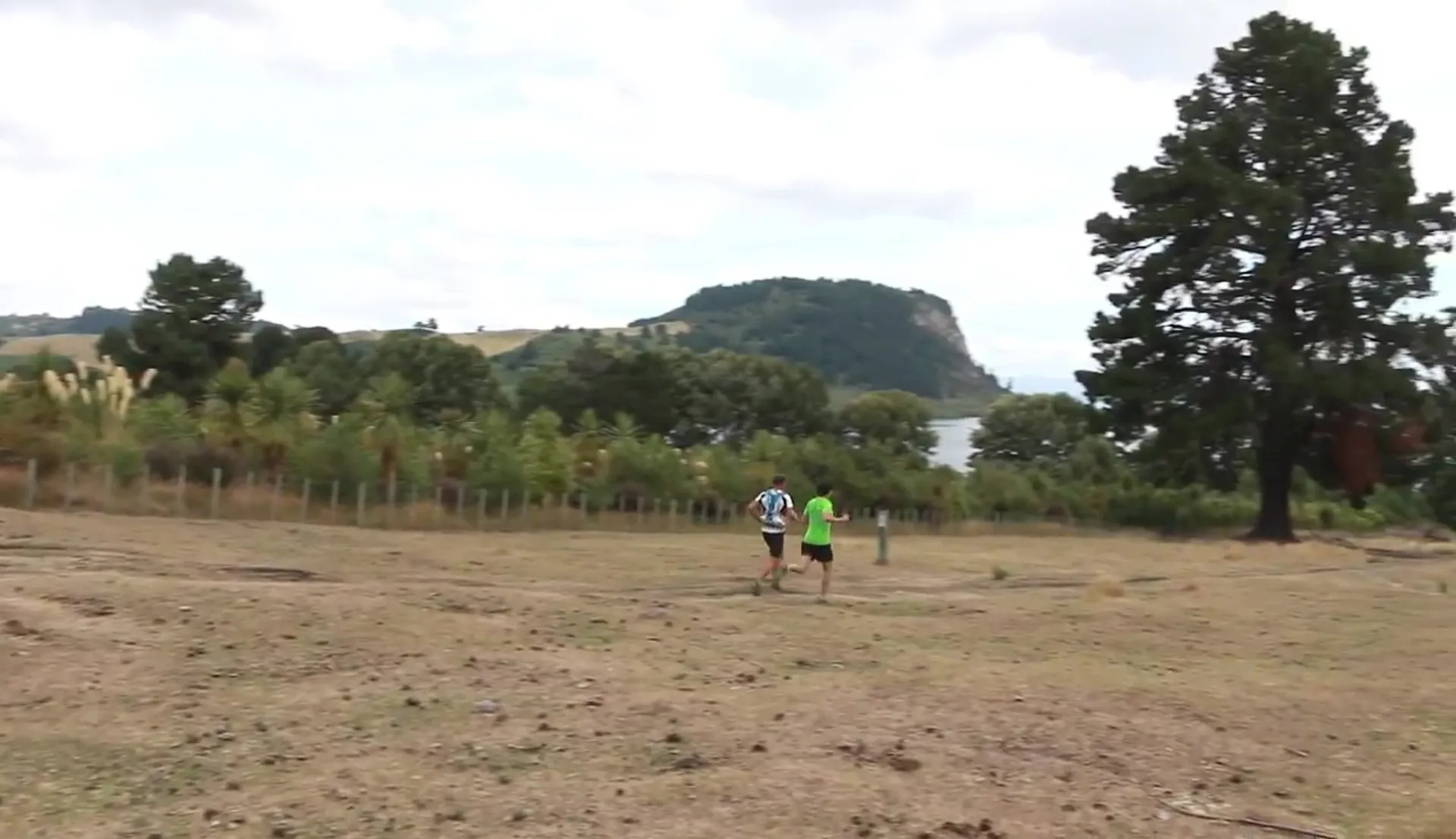 The image depicts a rural landscape with a variety of natural elements. Two people are