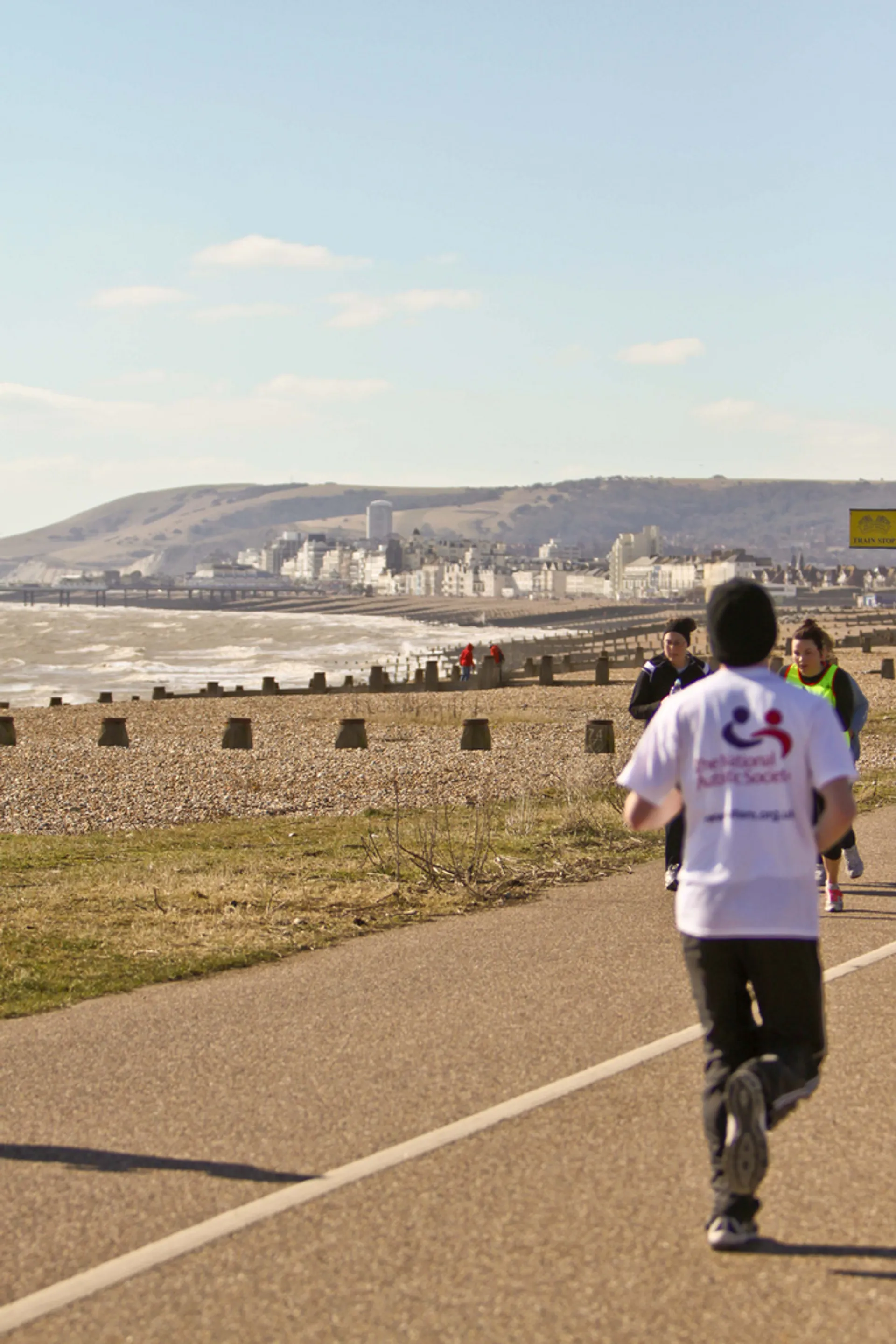 In the image, we see a person running on a paved pathway by the beach