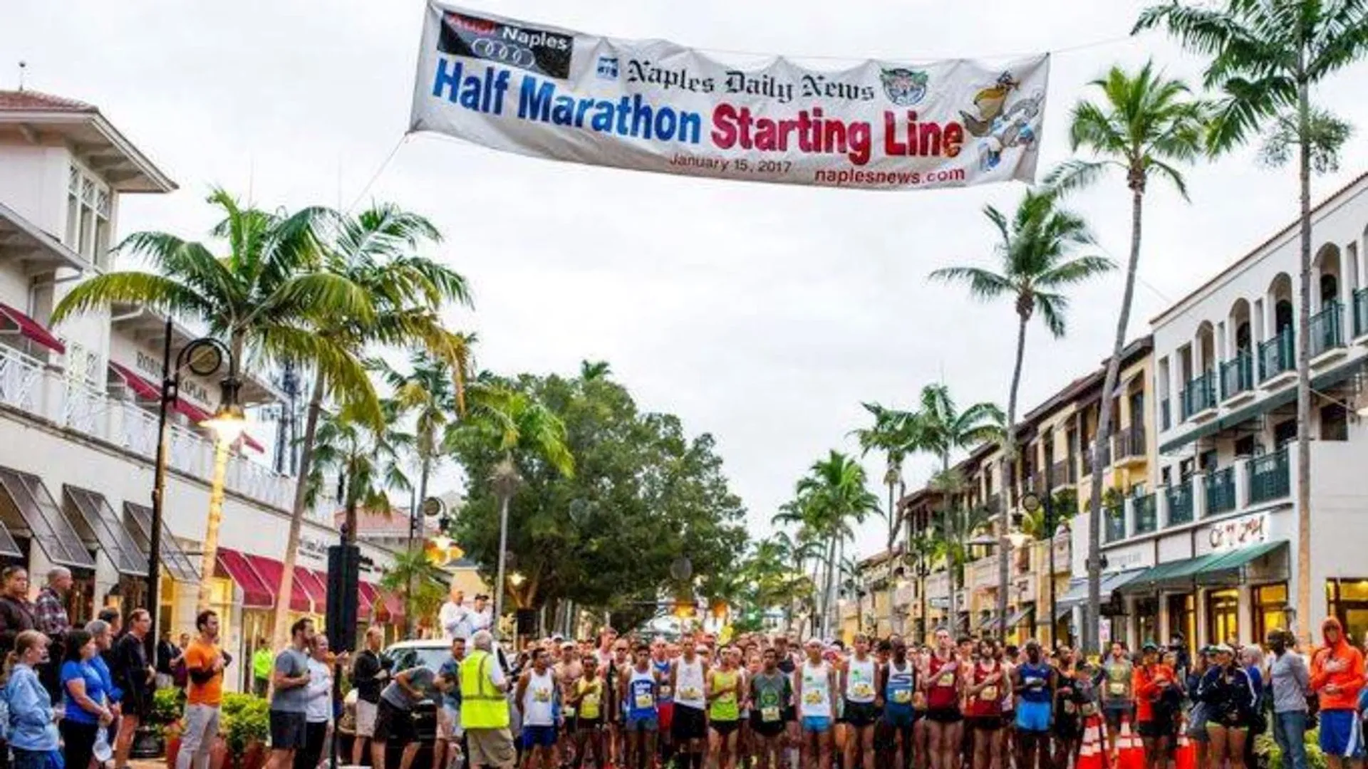 The image shows a group of runners gathered at the starting line of a half marathon