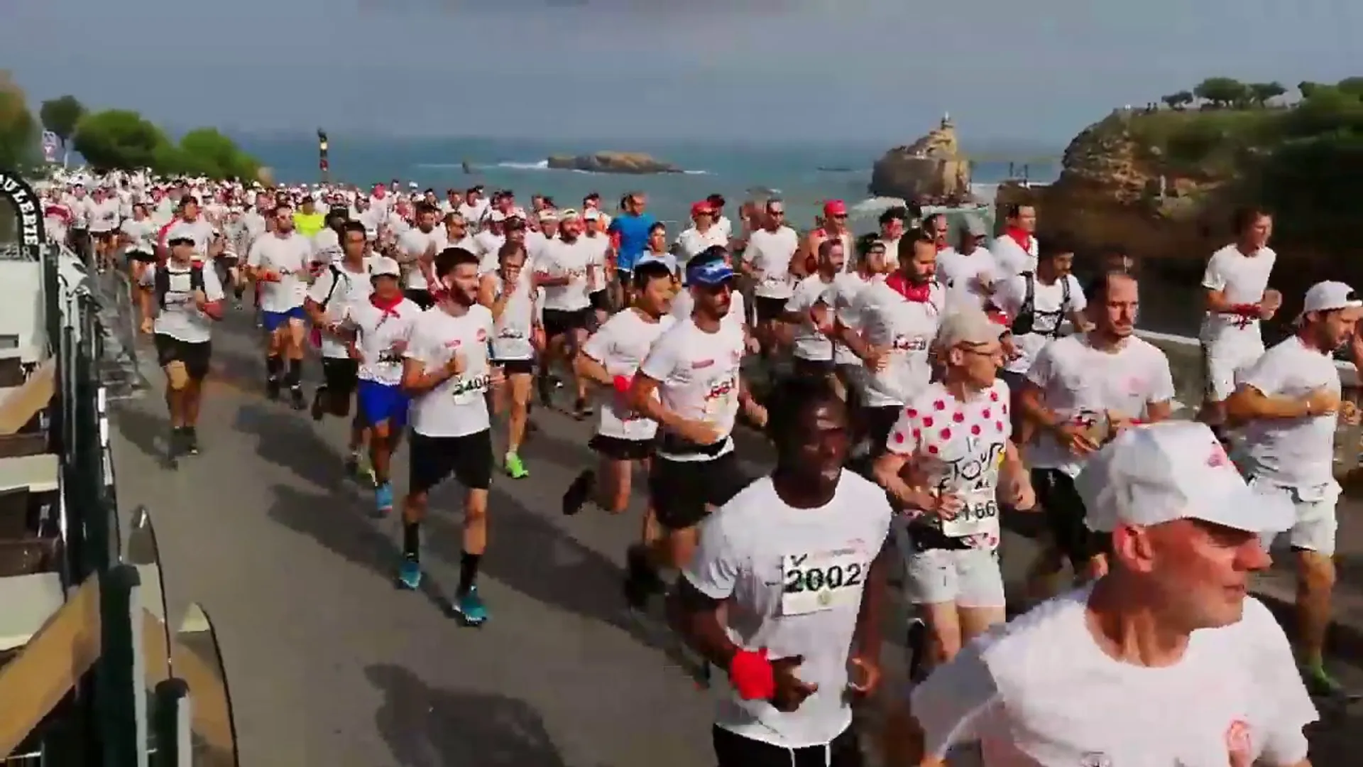 The image shows a large group of people participating in a running event. The participants