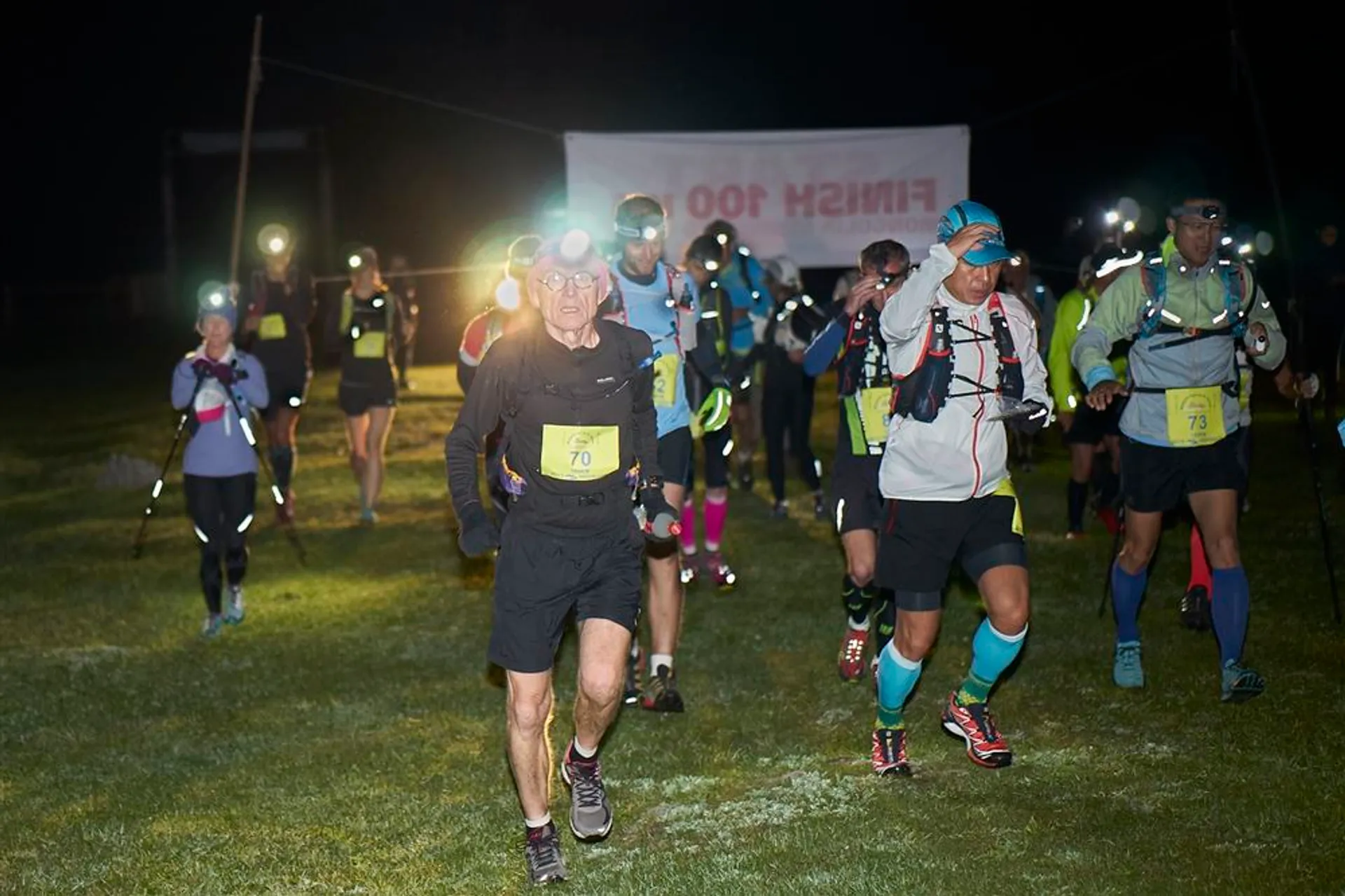 The image depicts a group of runners or participants in a night race or event.