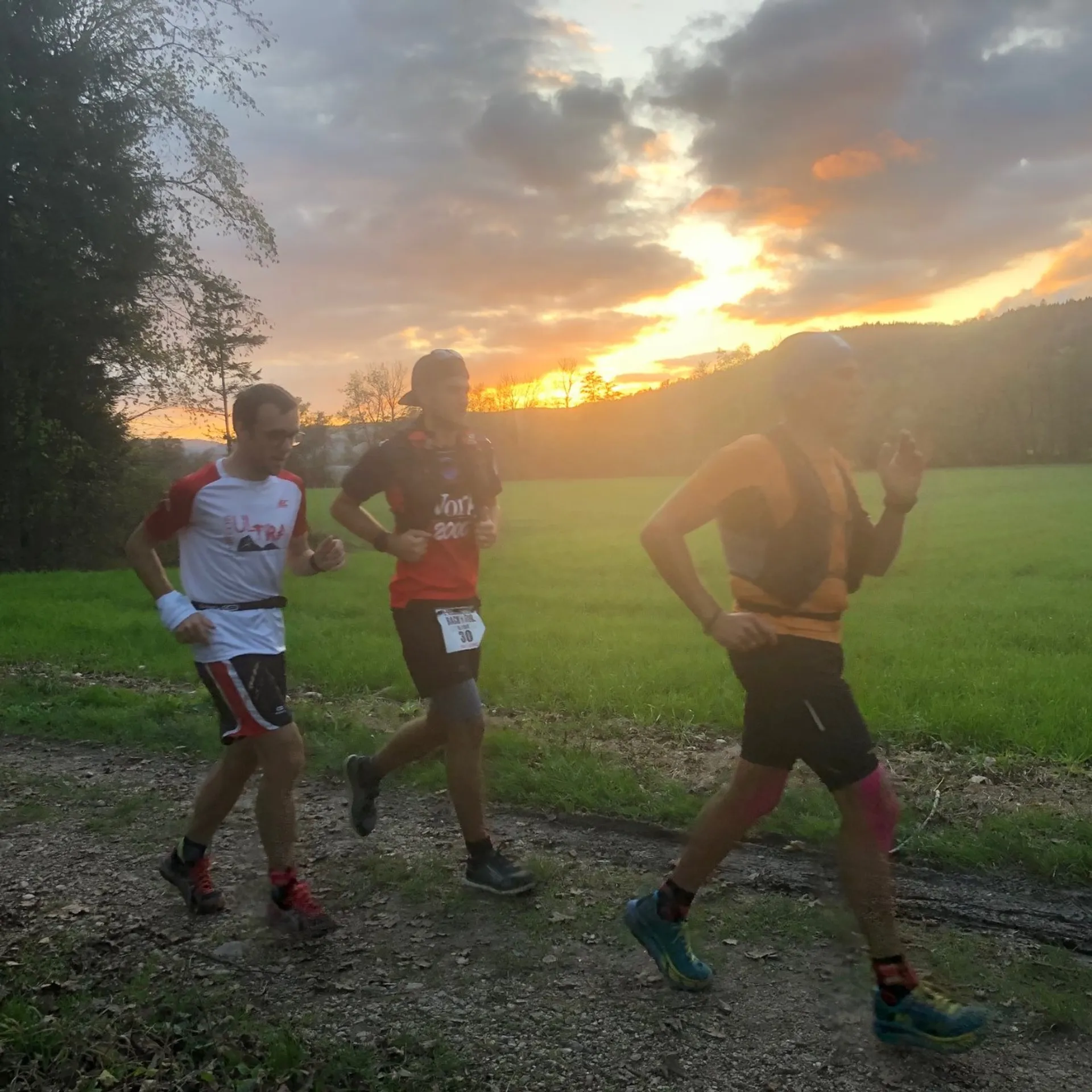 The image shows three individuals engaged in a running activity outdoors. They are wearing athletic
