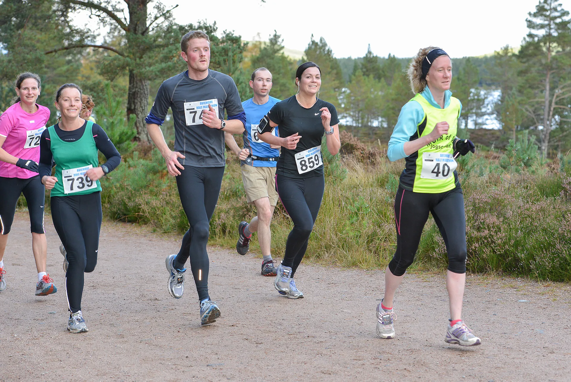 The image shows a group of people participating in a running event. The runners are