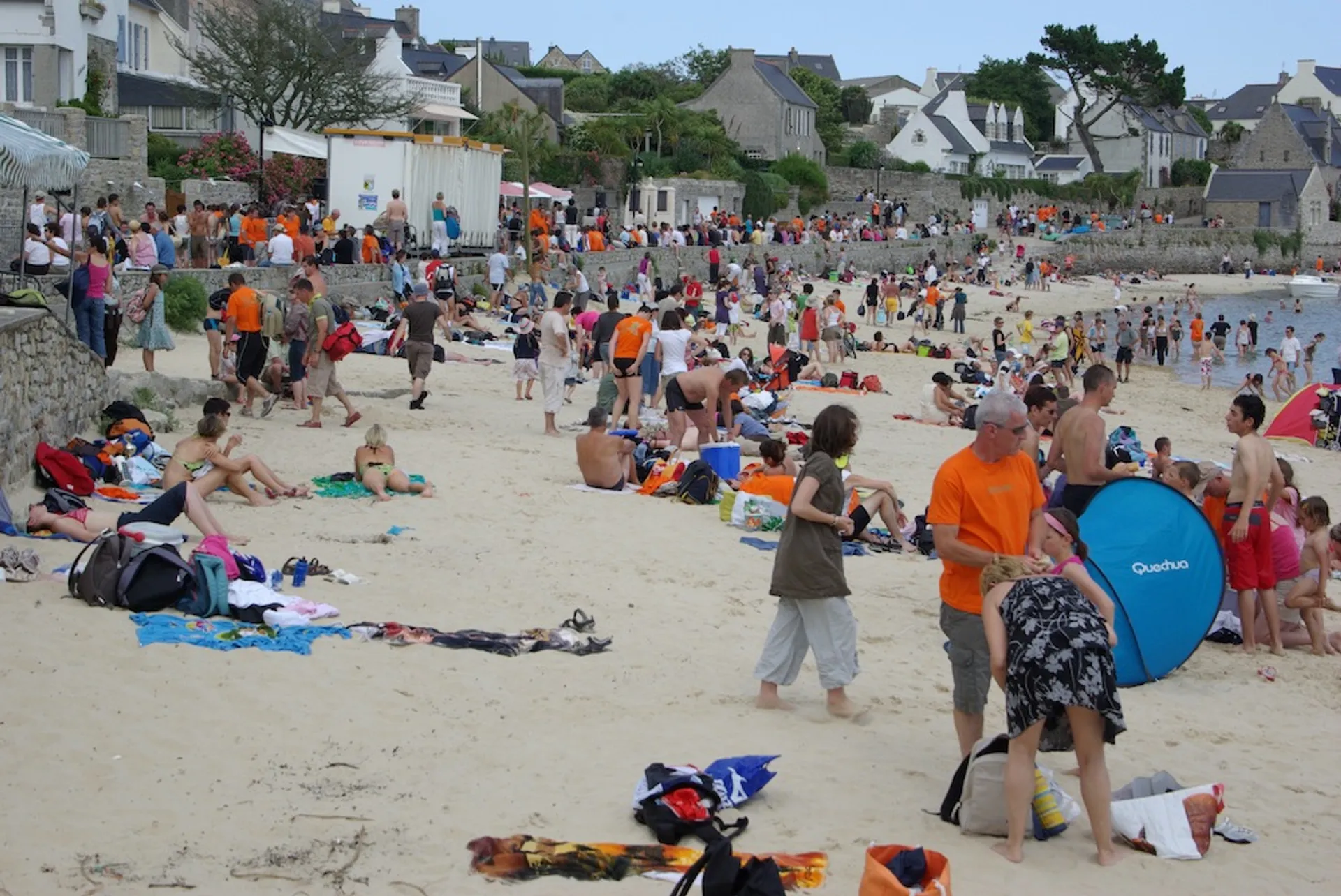 The image shows a crowded beach scene. Numerous people can be seen enjoying the beach