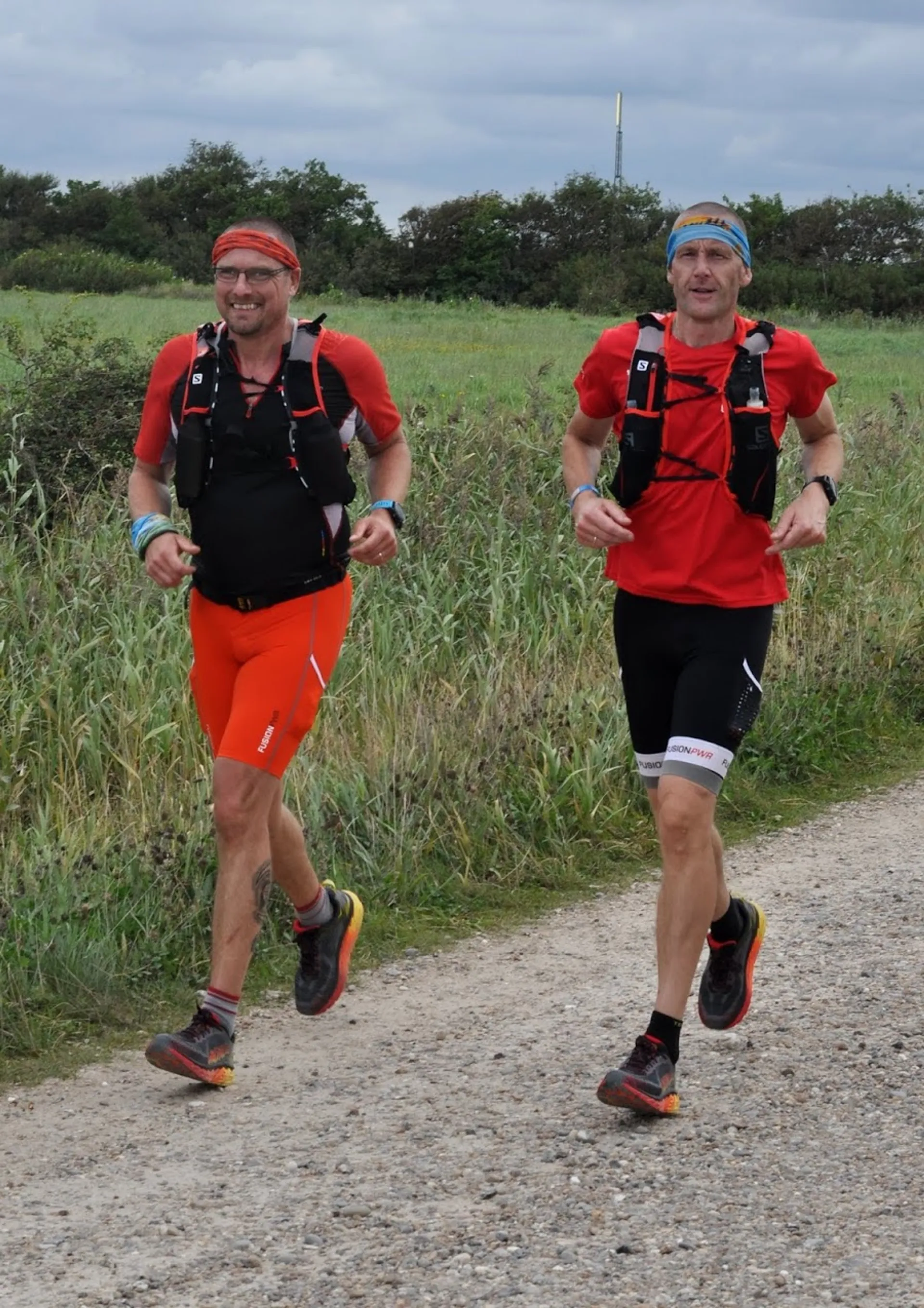 The image shows two individuals running outdoors on what appears to be a dirt or gravel