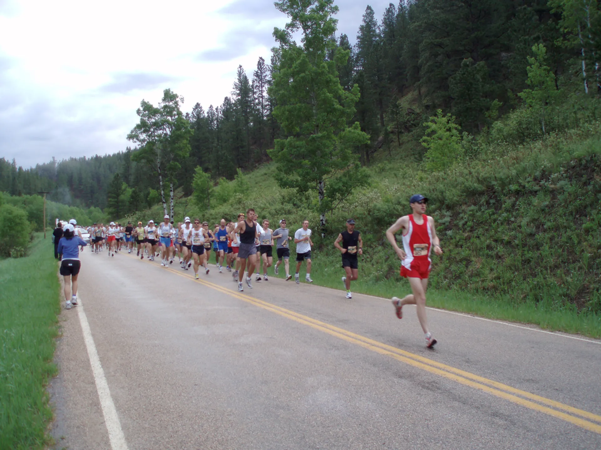 The image shows a group of runners participating in a road running event. They are