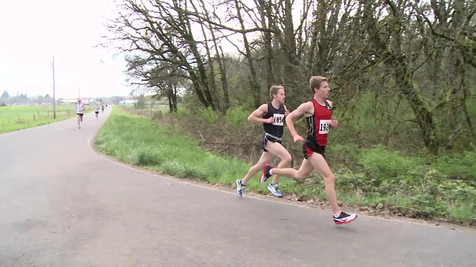 The image shows two runners in a race, with one athlete slightly leading the other