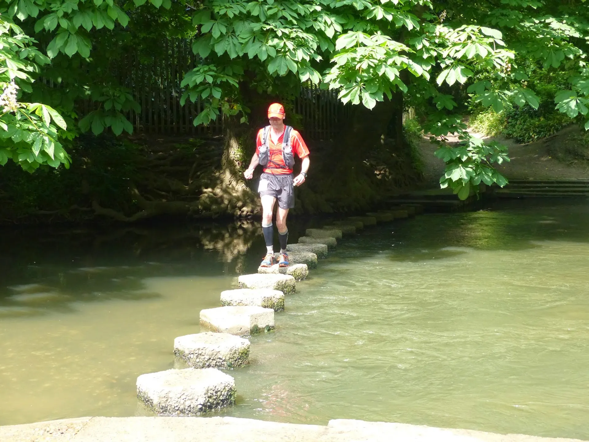 In the image, there is an individual walking across a small body of water using