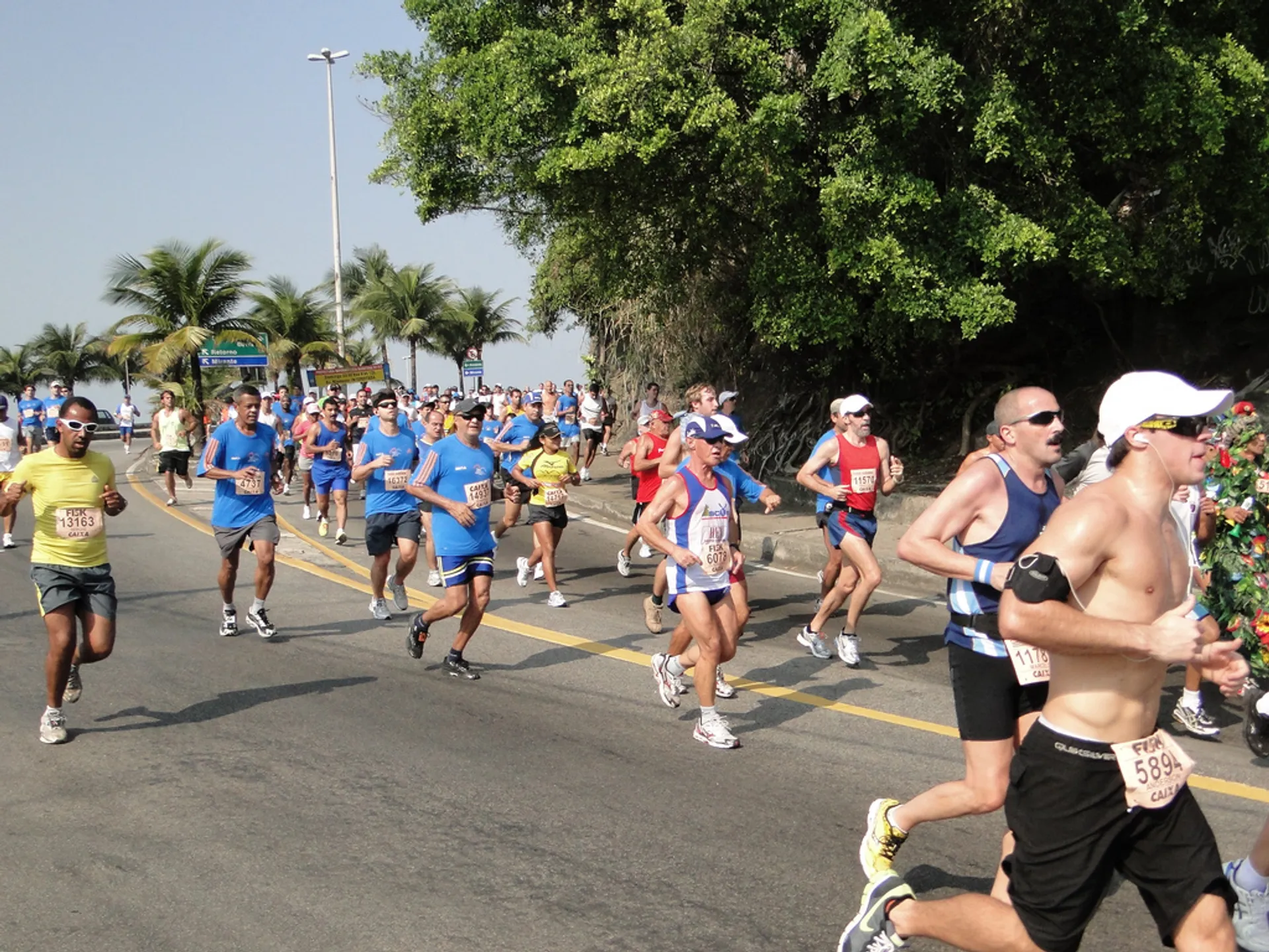 The image depicts a group of people participating in a road race or running event.