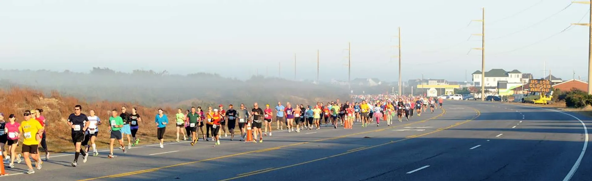 The image shows a group of people participating in a road race. They are running