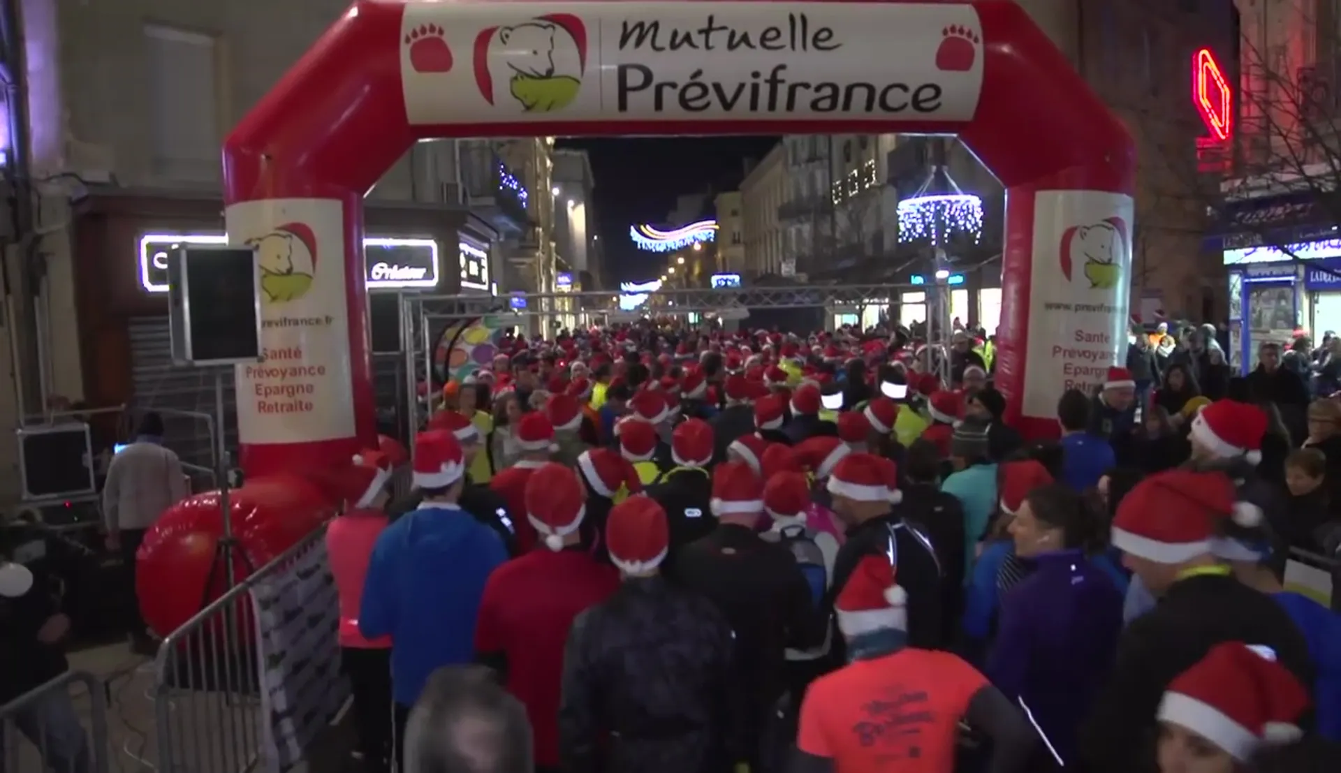 The image shows a group of people gathered at the starting line of a running event