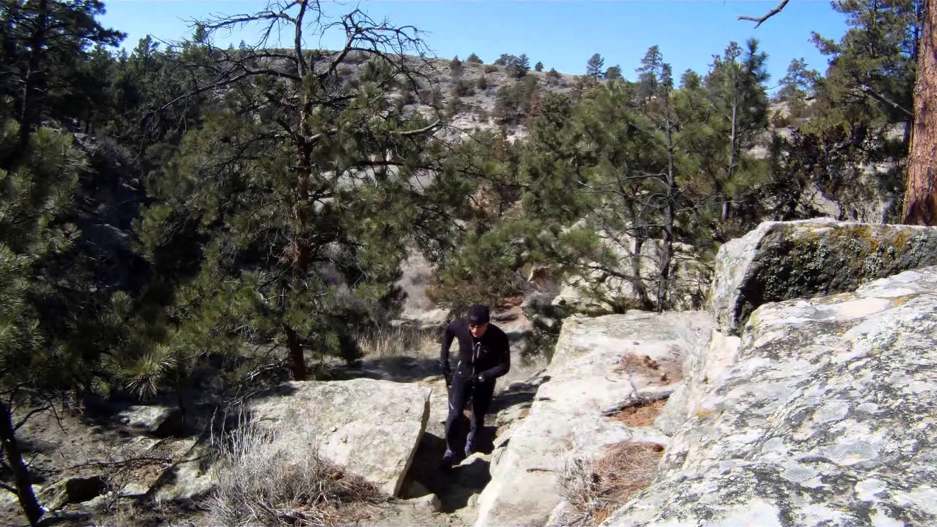 The image shows a person hiking or walking in a rugged, natural setting. They