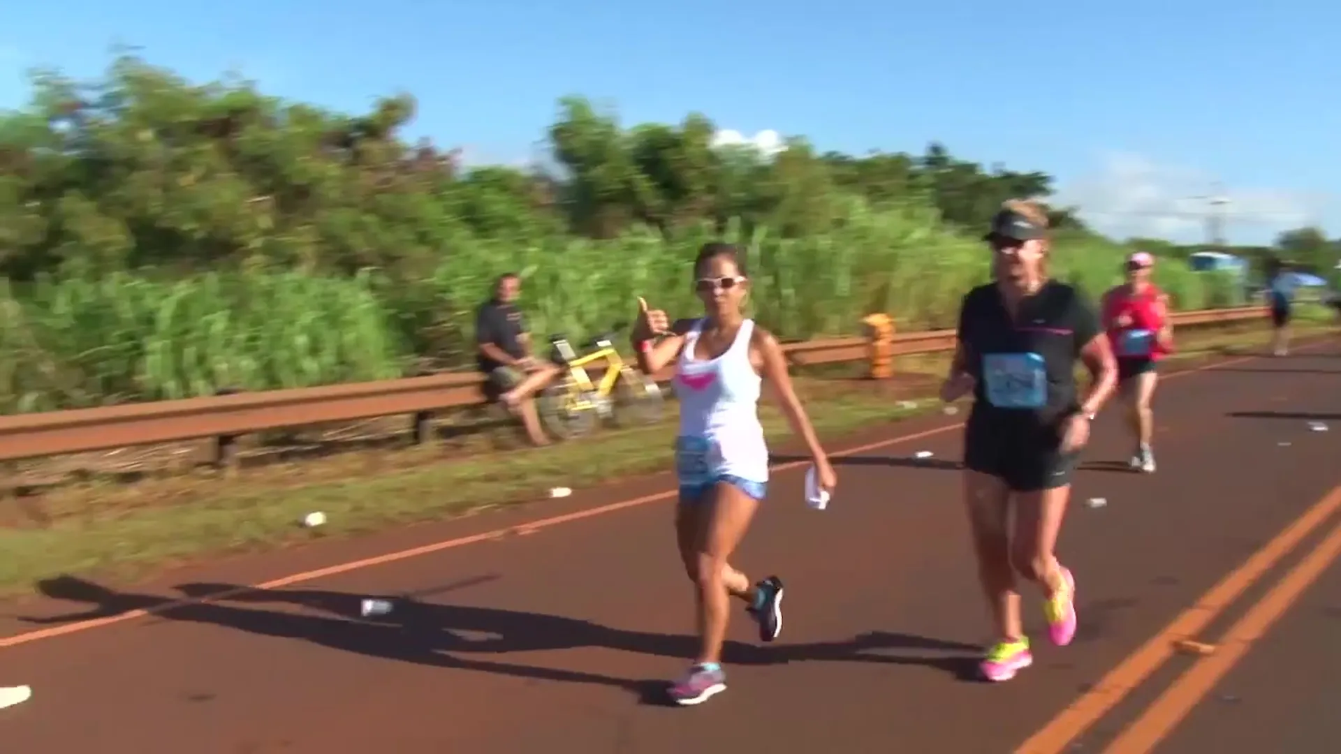 The image shows two people participating in a running event or marathon. They are running