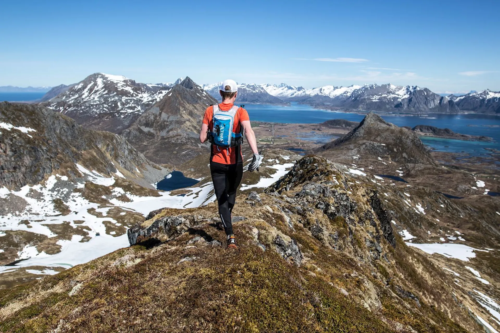 The image shows an individual hiking on a mountain ridge. The hiker is dressed