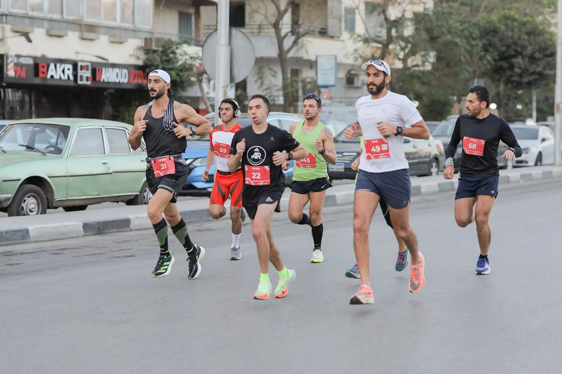 The image shows a group of runners participating in a road race. They are running