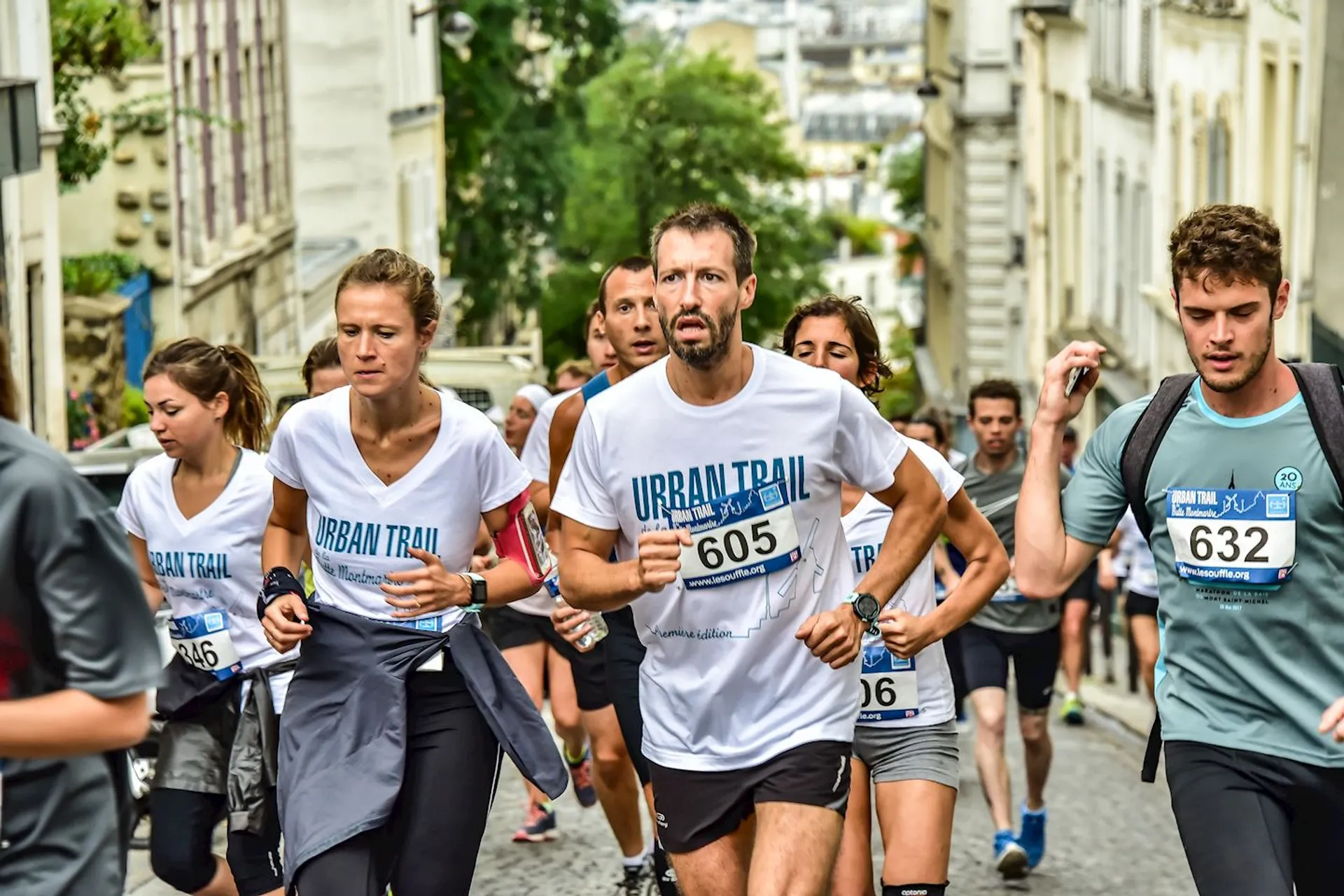 The image depicts a group of runners participating in an urban trail running event. The