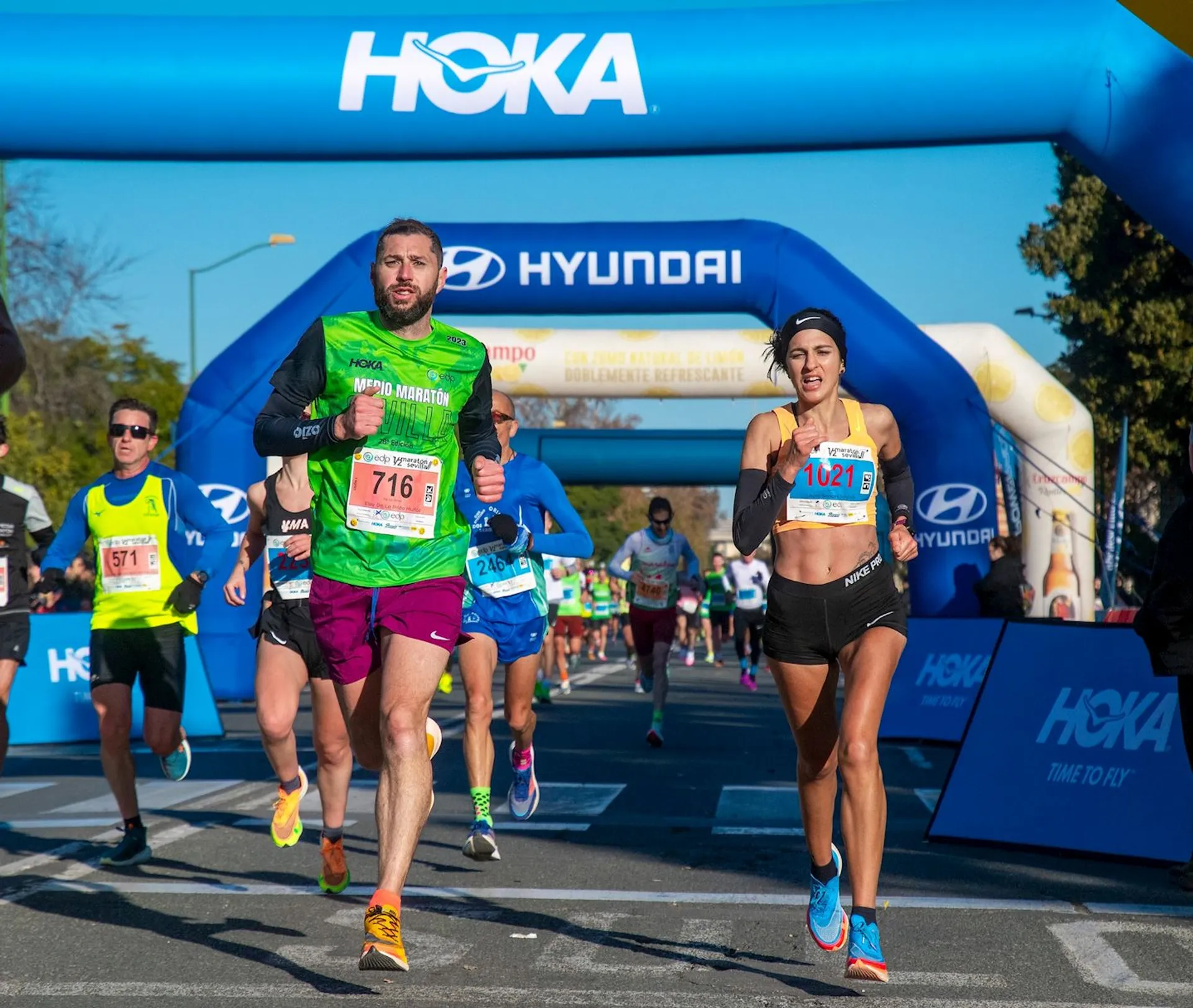 The image shows a running event with participants crossing a finish line or a checkpoint.