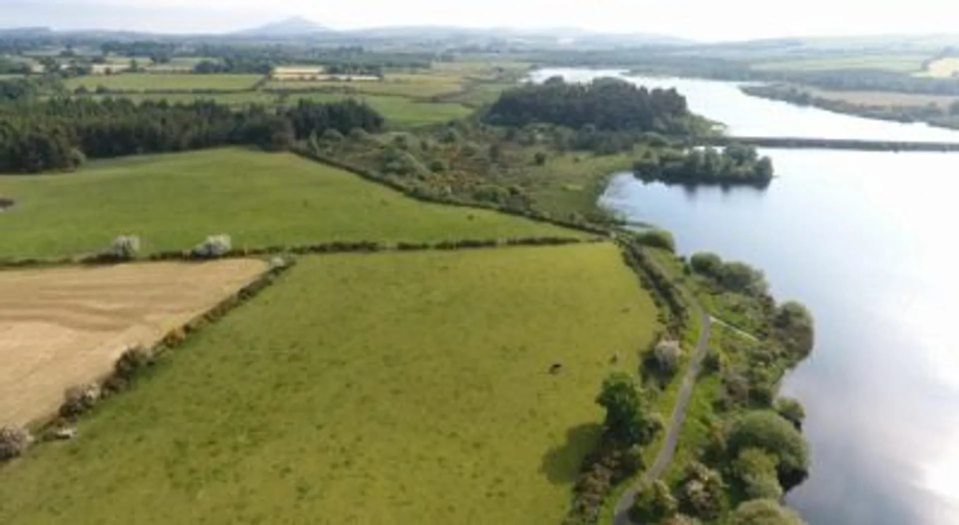 The image shows a scenic countryside view with a large body of water, possibly a