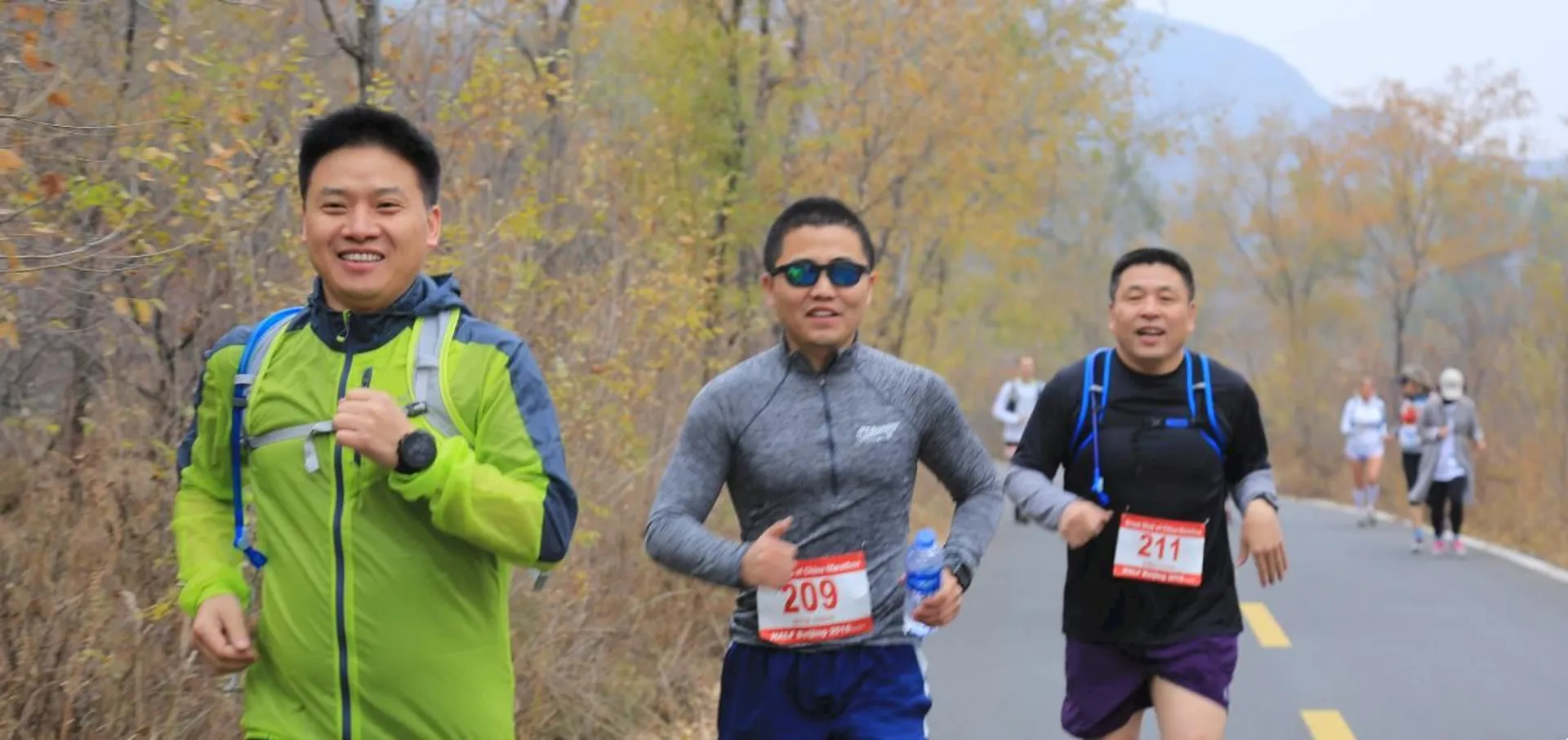 The image shows three individuals participating in what appears to be a running event or marathon
