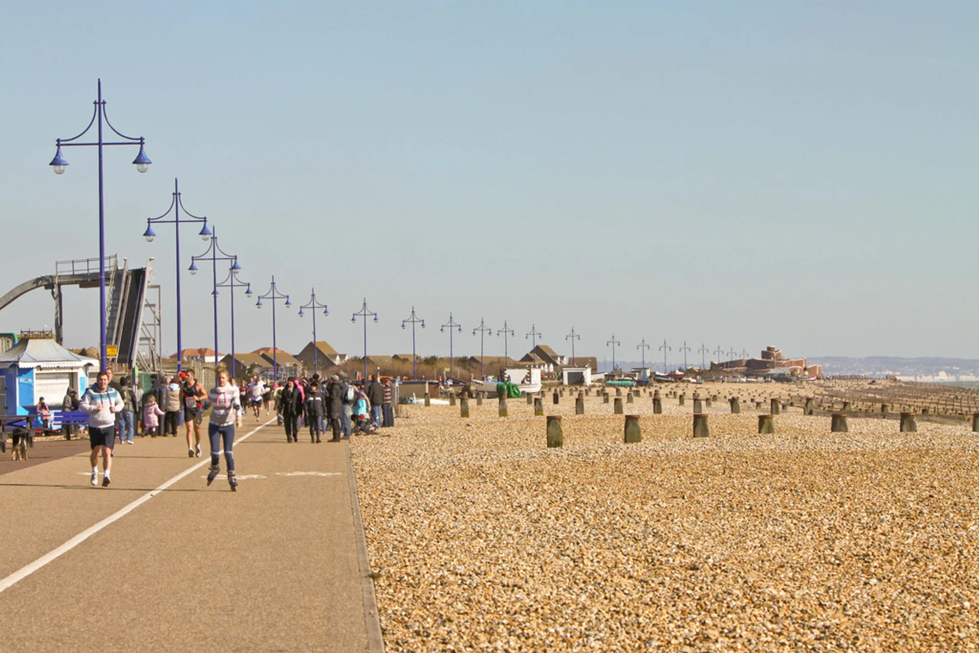 In this image, there is a seaside promenade with people walking along it.