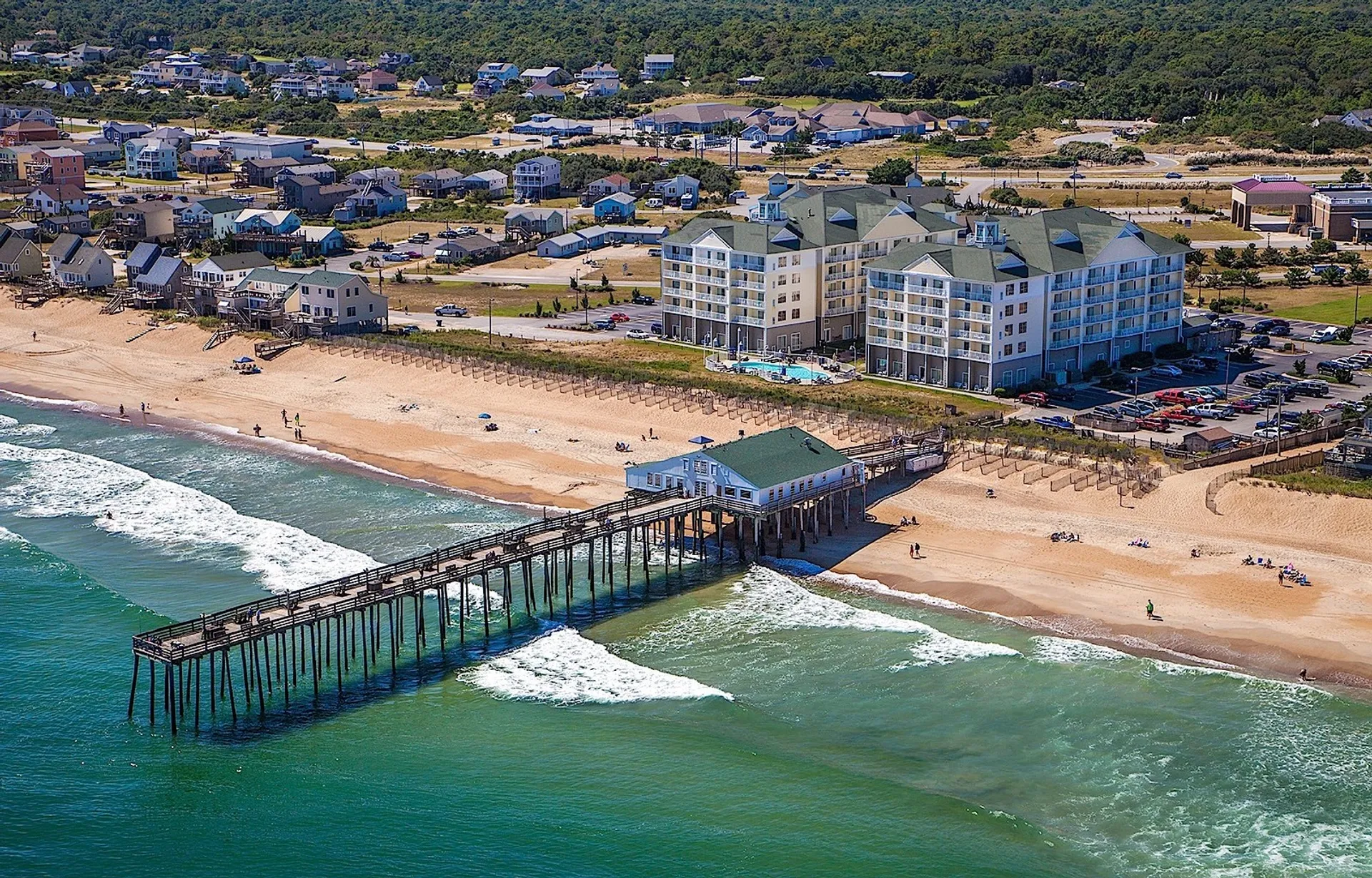 The image shows an aerial view of a coastal area. It features a sandy beach