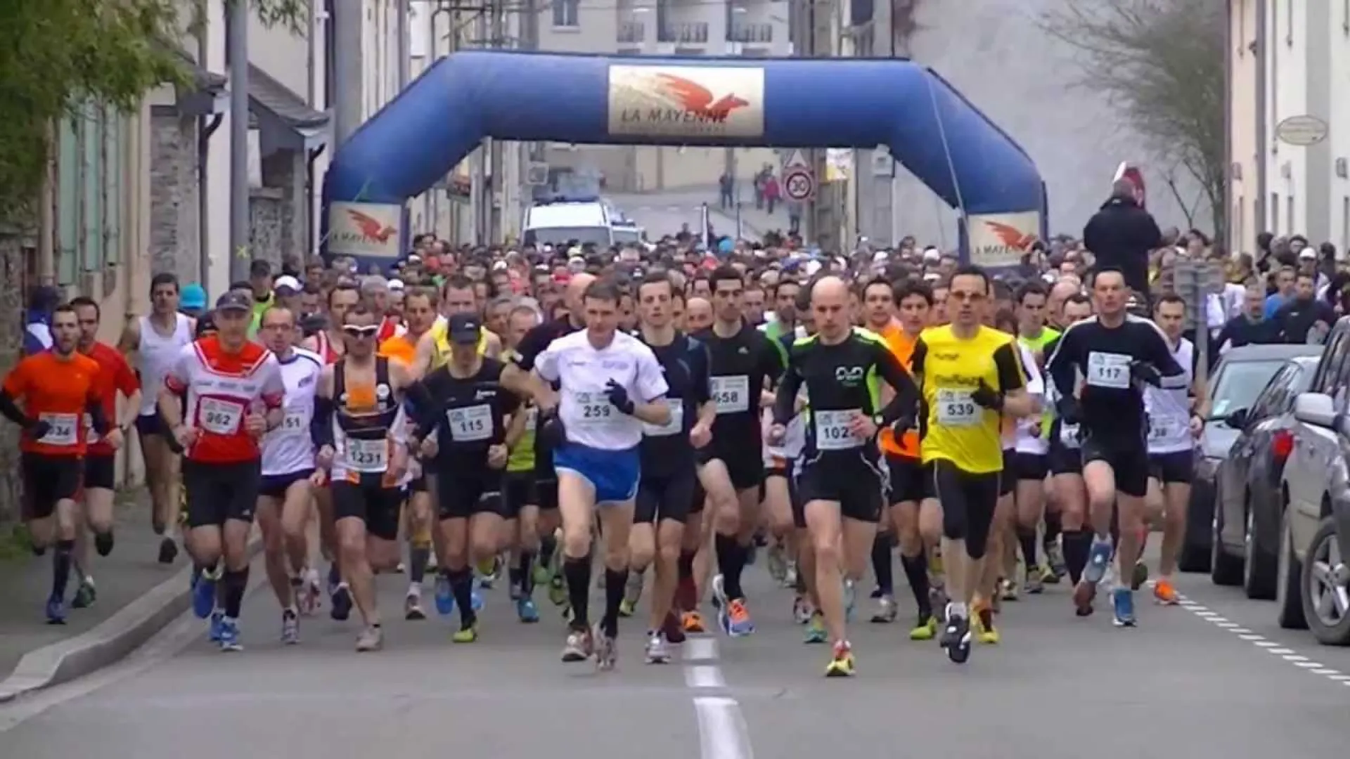The image shows a group of runners participating in a road race. They've just