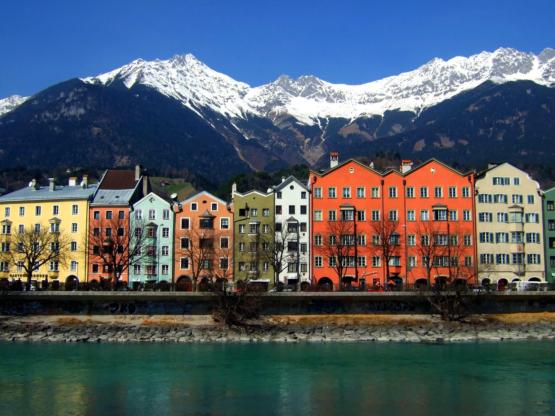The image depicts a picturesque view of a row of colorful buildings in the foreground,